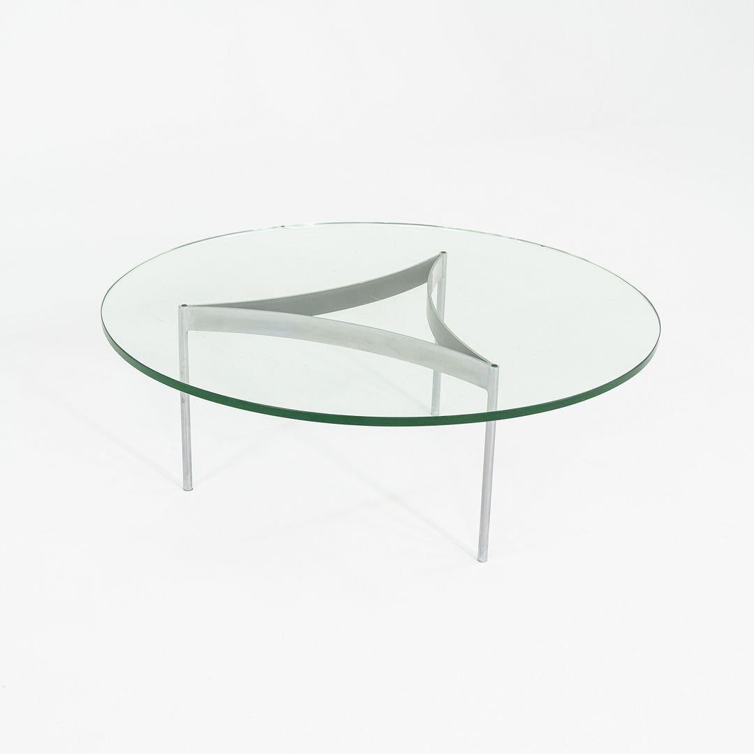 Il s'agit d'une table basse ronde en acier inoxydable chromé et verre, datant des années 1960. Le designer et le fabricant sont inconnus, mais le design rappelle les œuvres de Fabricius et Kastholm, Ward Bennett et Laverne Originals. La base à trois