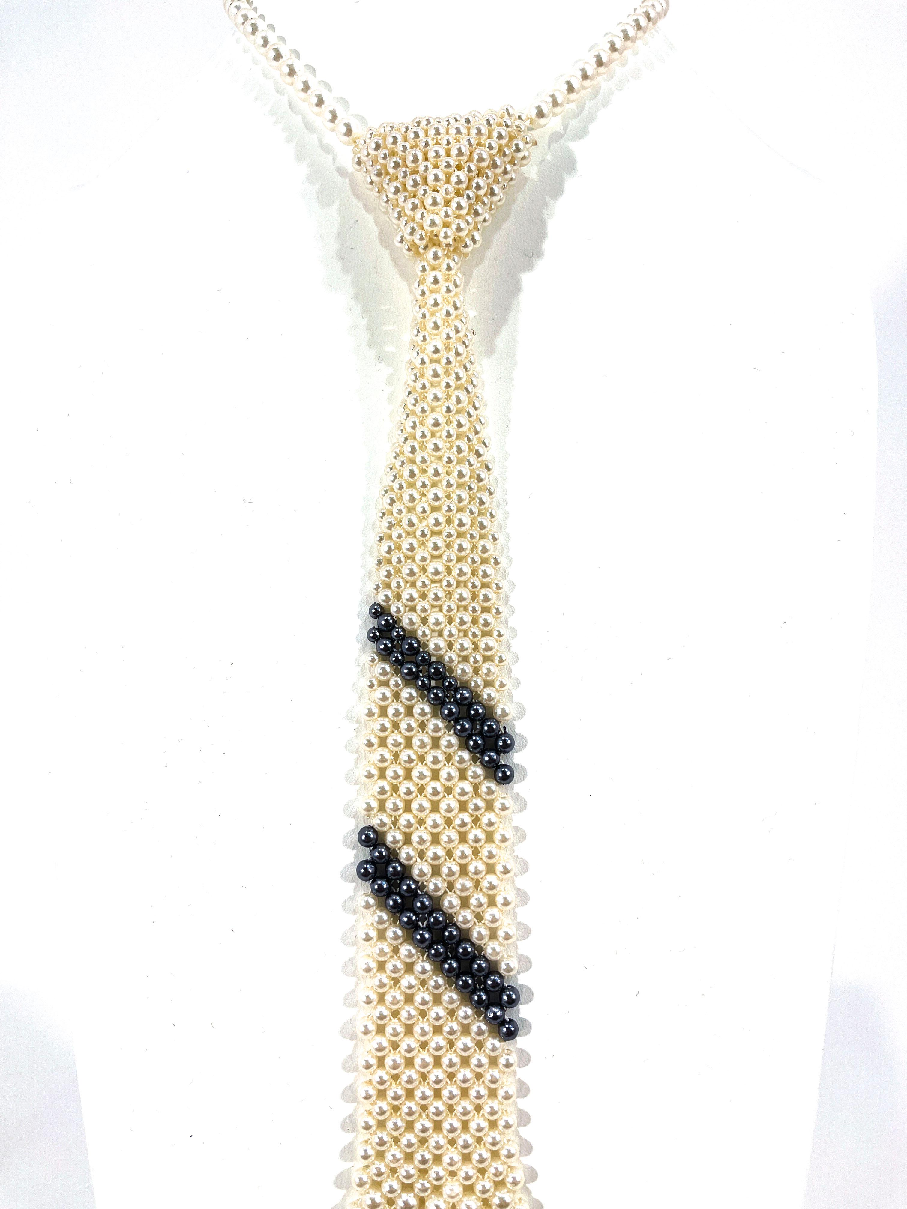 1960's glass pearl necktie necklace with graduating pearl size and two stripes of gray pearls in the center.  The actual length of the necklace that is adjustable around the neck can accommodate up to a 17 inch neck. The dimensions of the tie are
