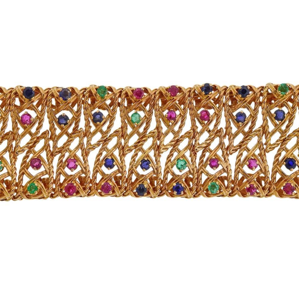 Vintage, circa 1960s, 18k yellow gold wide bracelet. Decorated with rubies, blue sapphires and emeralds.  Bracelet is 7 1/8