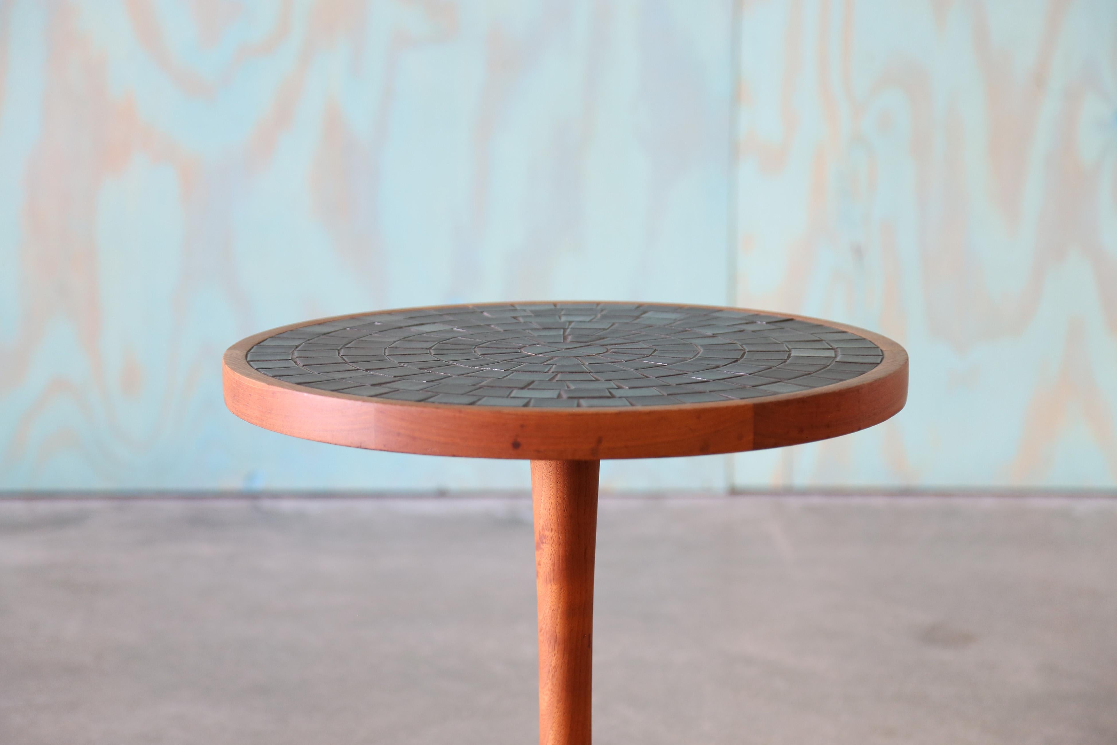 A 1960s tile table designed by Jane and Gordon Martz for Marshall Studios in Veedersburg Indiana.  This table in walnut and dark gray glazed tiles.  A nice size and elegant form with a slightly tapered stem supported by a weighted base. The top