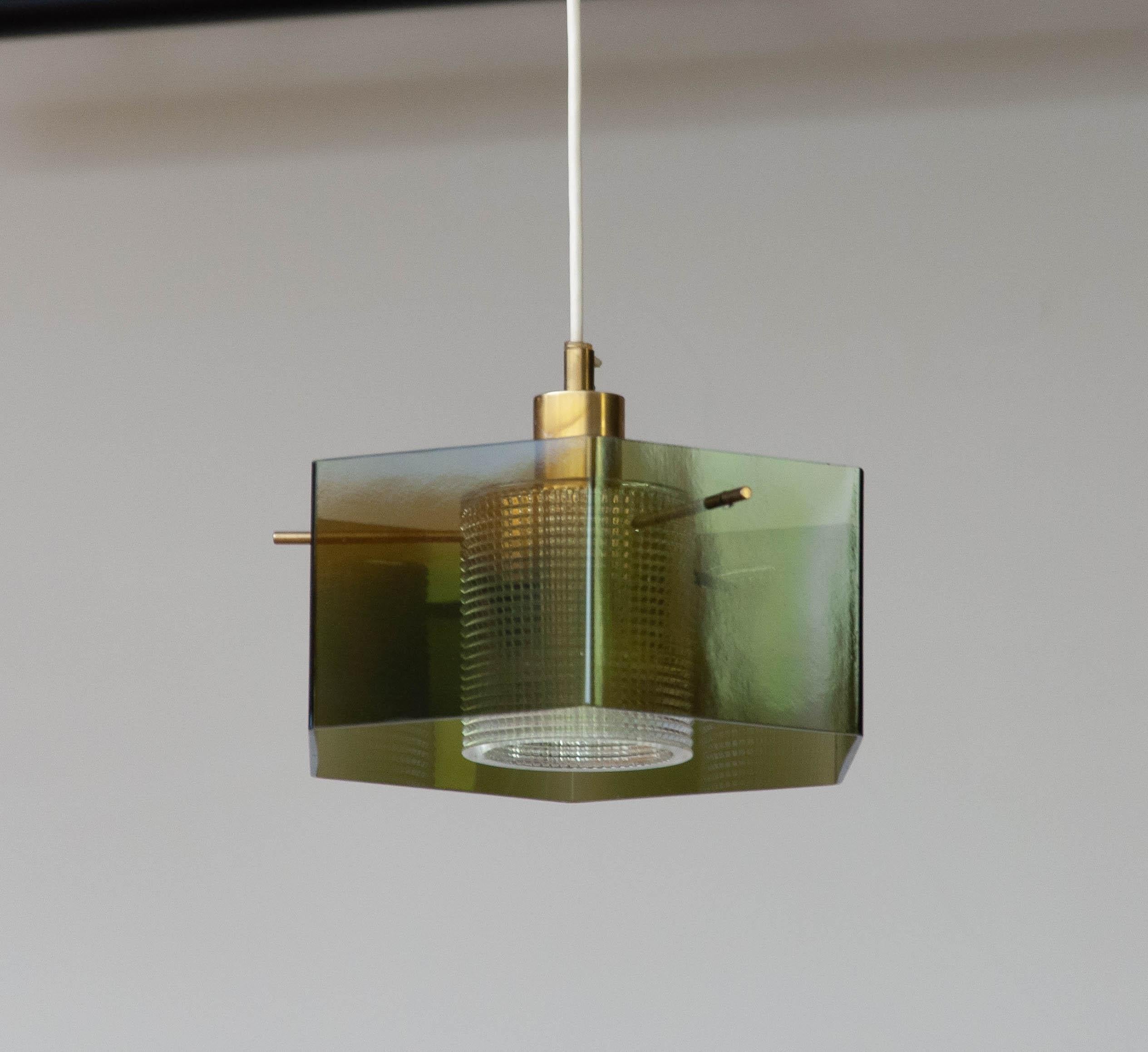 Great art-glass pendant designed by Carl Fagerlund for Orrefors in Sweden in the 1960's.
Inside the green hexagonal outer shade is an heavy clear art glass cilinder.

Both glass shades are hanging on three brass bars who are mounted to a brass