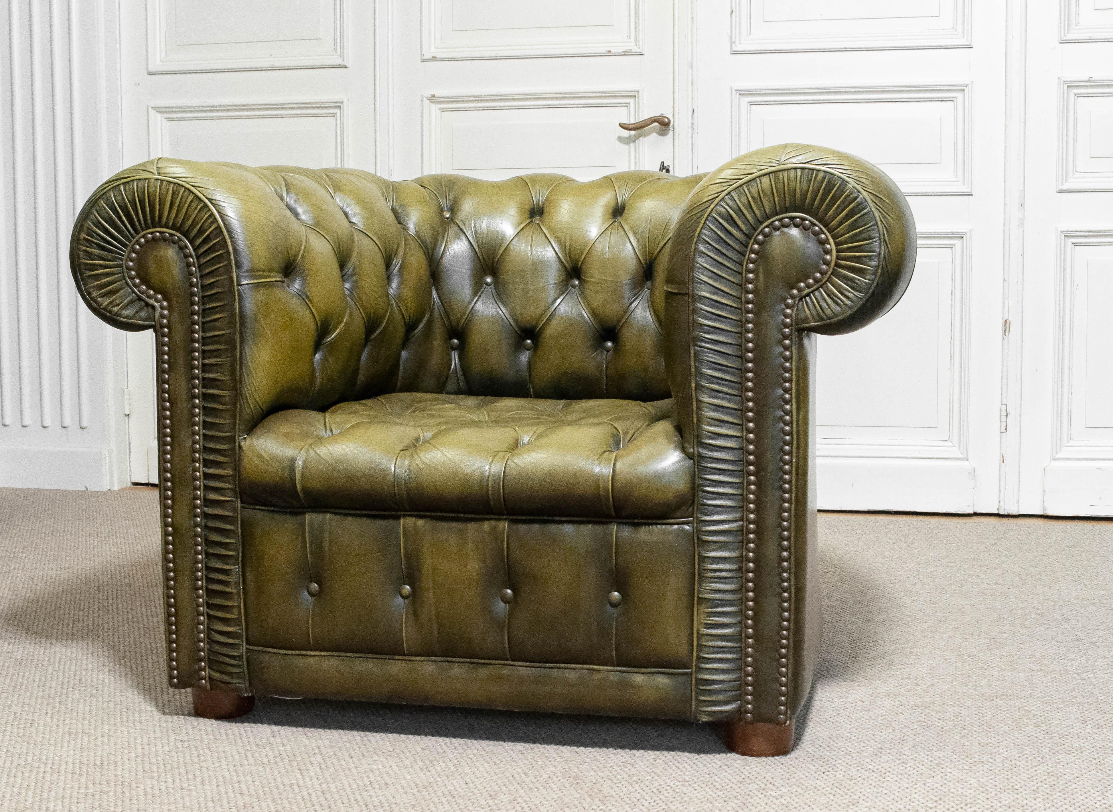 A classic 1960s Chesterfield club armchair upholstered in beautifully aged, green-dyed vintage leather. This piece captures the timeless elegance of the Chesterfield design with its deep button-tufted backrest and seat, generous rolled arms, and