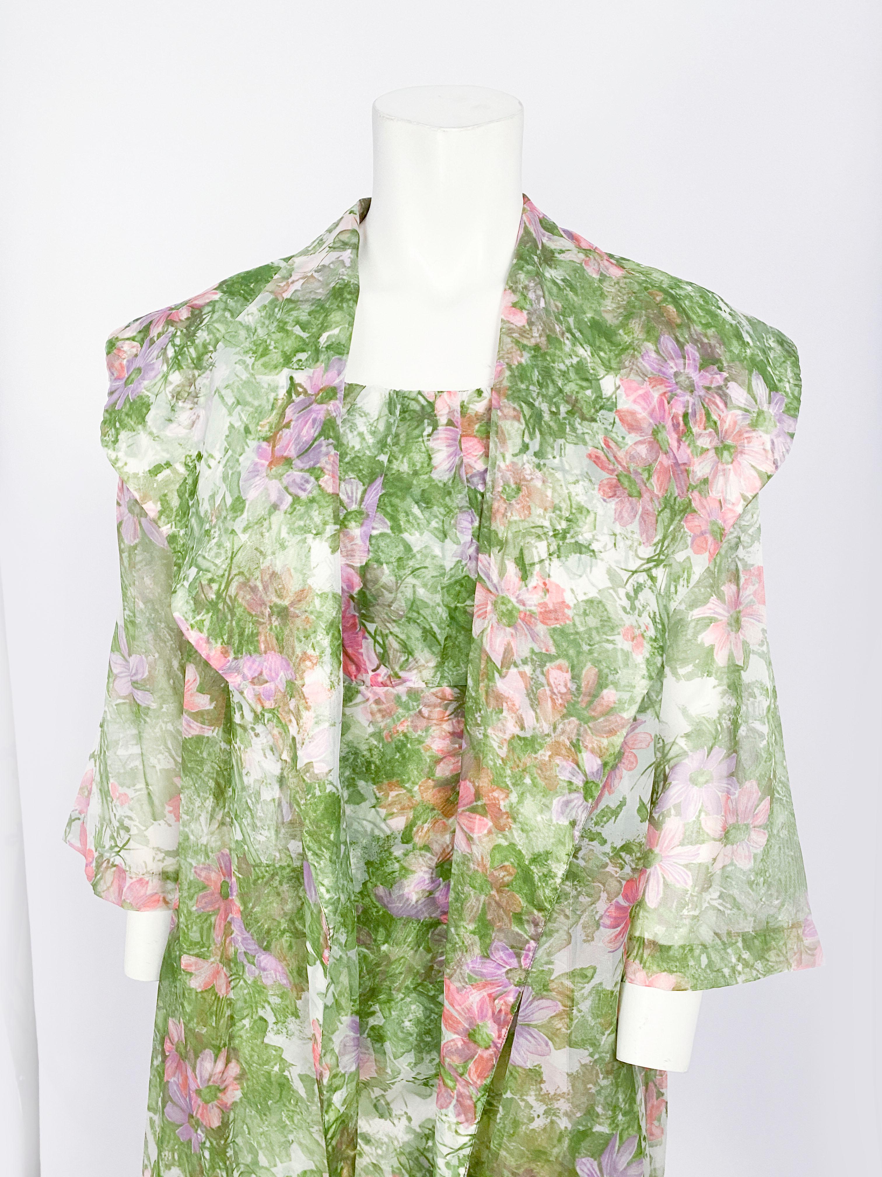 1960s floral printed polyester chiffon dress featuring green, pink and lavender tones. The sleeveless dress has a gathered neckline, an empire waist, a decorative bow, and is fully lined. The swing coat is light and sheer with 3/4 -length sleeves