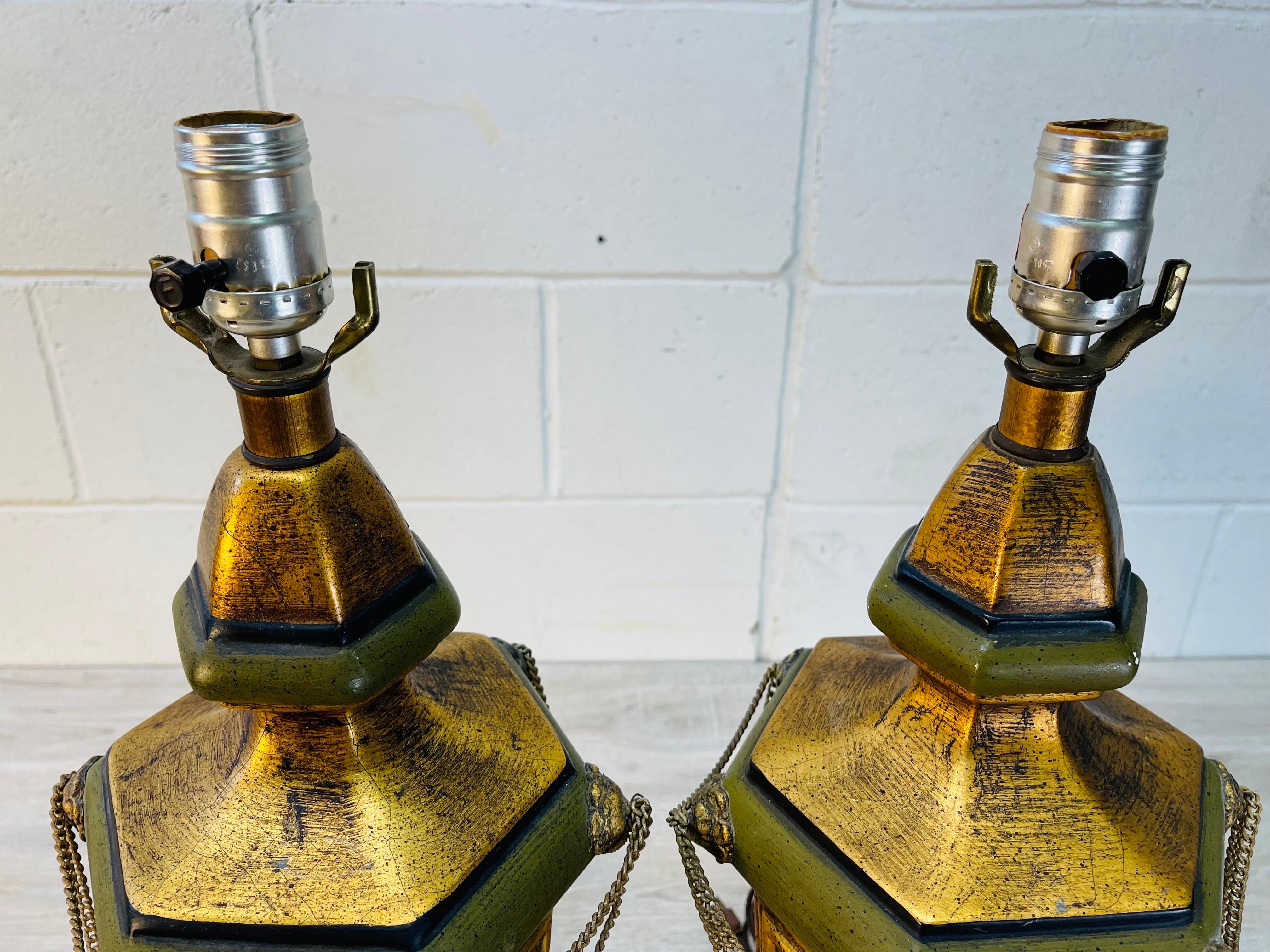Vintage 1960s pair of green and gold urn style table lamps with swag metal accents. The lamps are wired for the US and in working condition. They use a standard 100W bulb. The lamps do not have harps but do come with the original shades. The shades