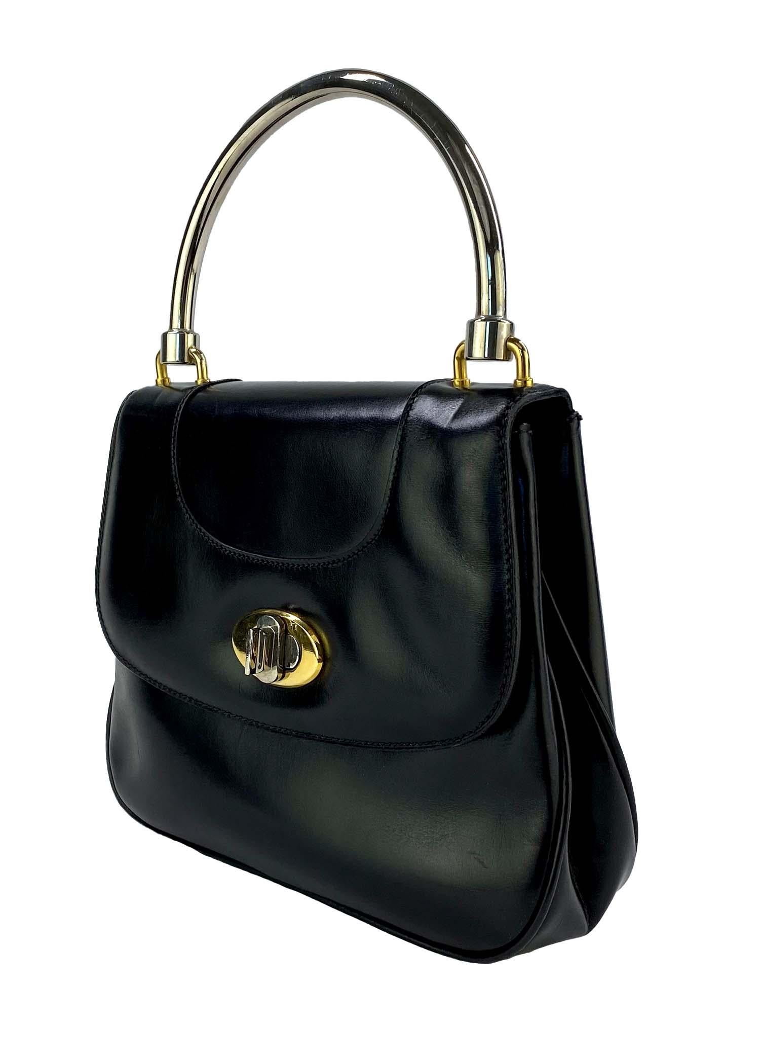 TheRealList presents: a vintage 1960s Gucci structured leather top handle bag. This classicly designed bag features a dual-tone metal handle and closure. The dark black leather has a semigloss finish to perfectly match the shine of the hardware.