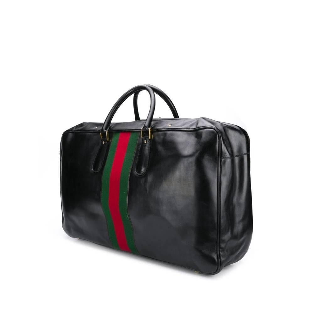 Gucci black leather travel bag with green and red Sylvie Web detail and zip and buckle closure. Two rigid handles and metal feet on the bottom. Interior with elastic compartments and garment straps.

The product has some scratches on the leather and