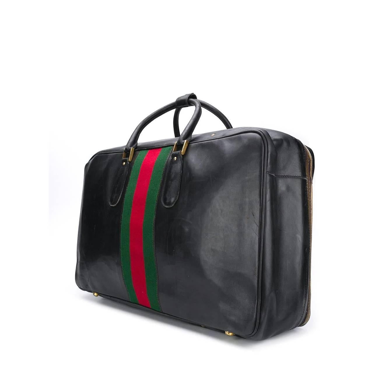 A.N.G.E.L.O. Vintage - ITALY 

Gucci black leather travel bag with green and red Sylvie Web detail and zip and buckle closure. Two rigid handles and metal feet on the bottom. Interior with elastic compartments and garment straps.

The product has