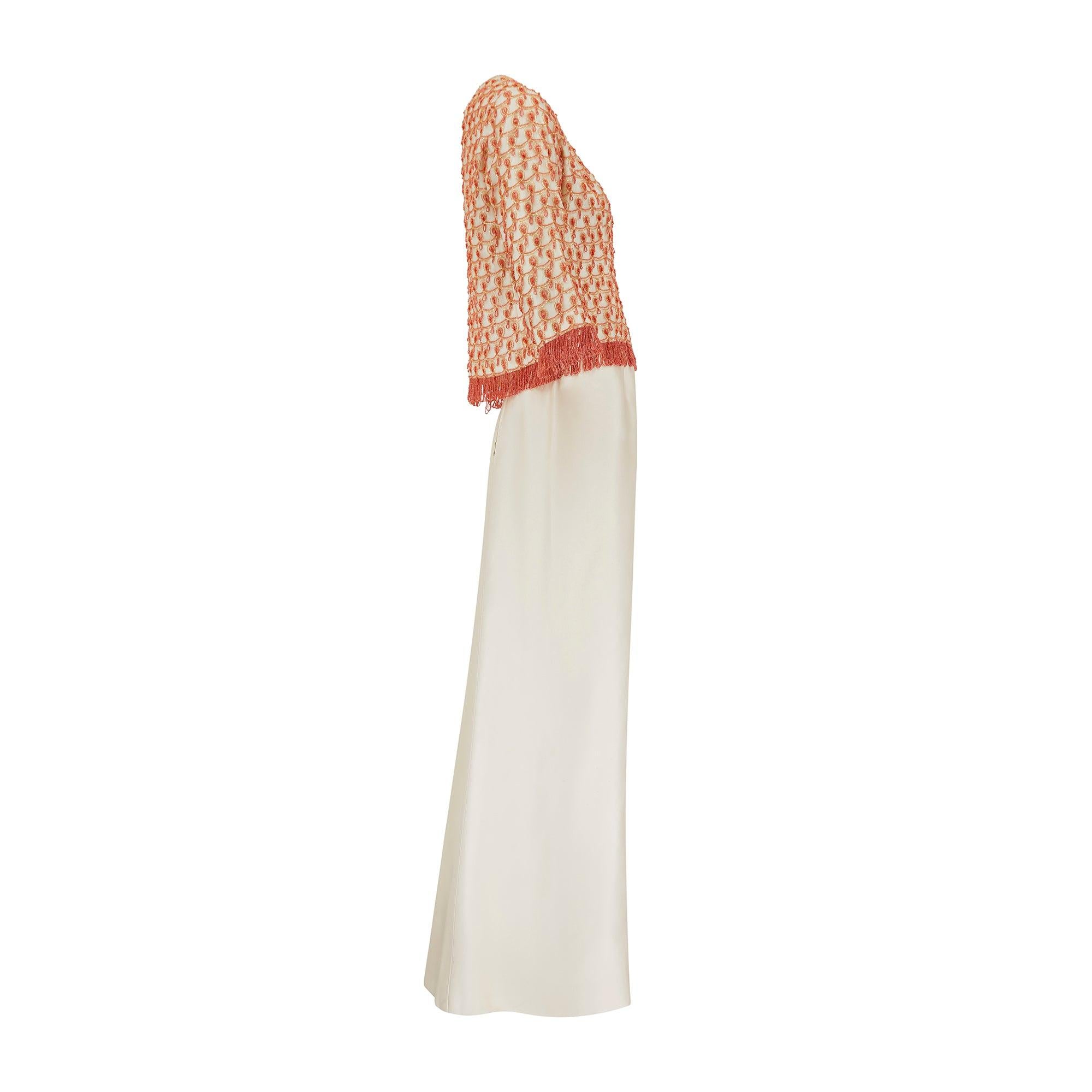 This mid to late 1960s couture ensemble was made by sophisticated Parisian atelier Guy Laroche. Composed of a skirt and three-quarter length sleeved top, it is crafted from luxurious pale champagne coloured silk which holds its shape. The