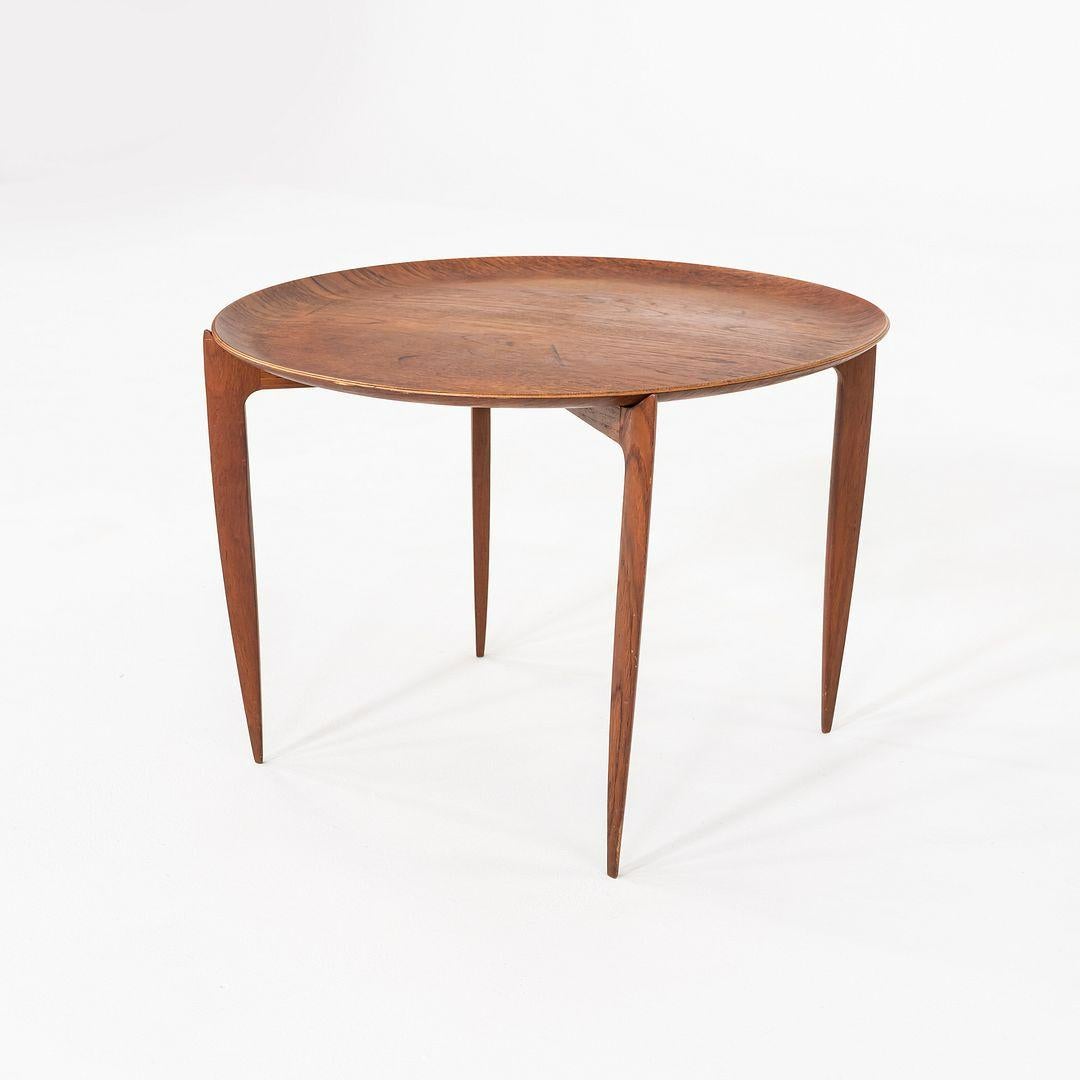 This is a Round Tray Top Table in Teak, Model 4508, designed by Hans Engholm and Svend Age Willumsen for Fritz Hansen in Denmark in 1958. The design incorporates a round removable tray top with a foldable four-legged stand. This piece was retailed
