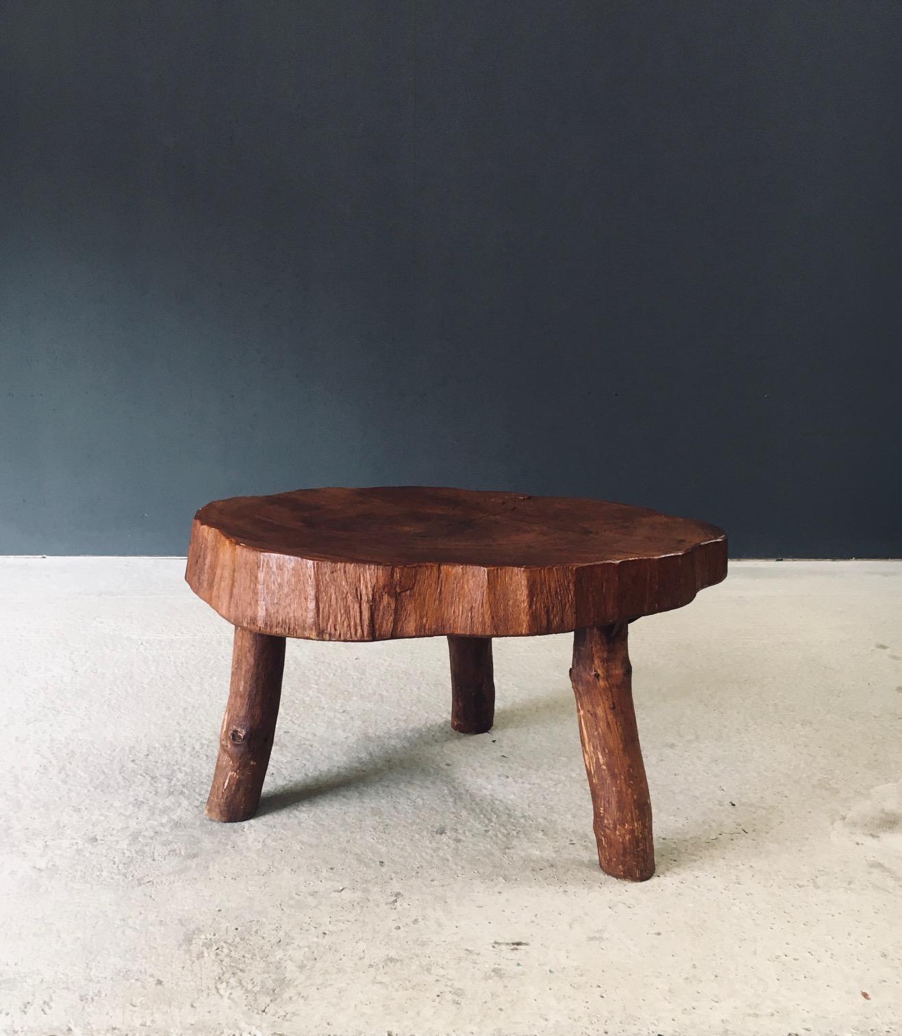 Vintage Midcentury Period Hand Crafted Tripod Teak Tree Trunk Coffee Table. Made in the 1960's period. Solid Teak wood tree trunk slab on 3 legs, fixed with metal spikes. This comes in very good, all original condition. With normal patina and wear