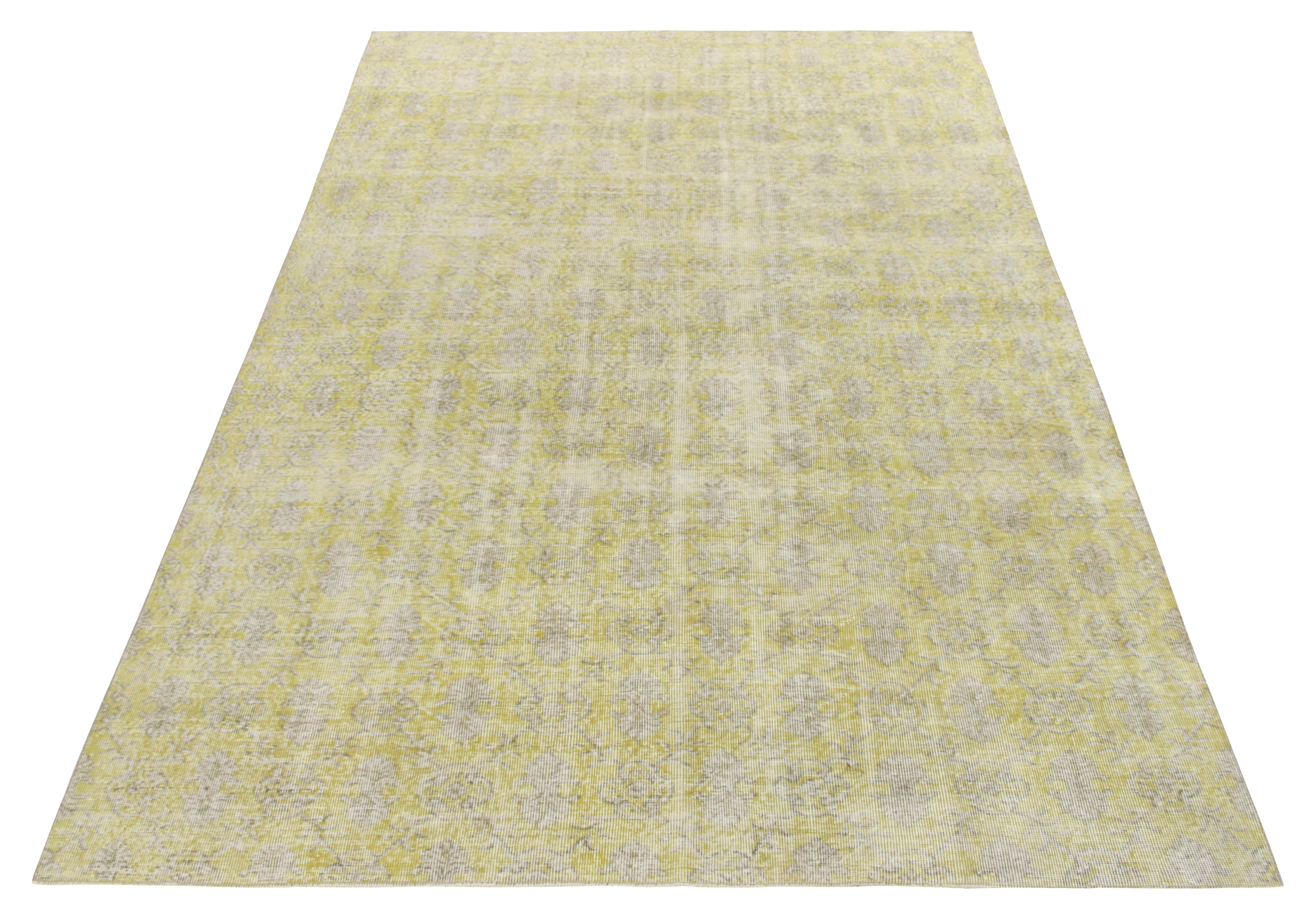 Hand-knotted in fine wool, this 7x11 vintage mid-century rug enjoys a subtle floral pattern in lemon and grey tones, perfectly complementing the distressed vibe of this mid century modern piece. Coming from one of the most venerated