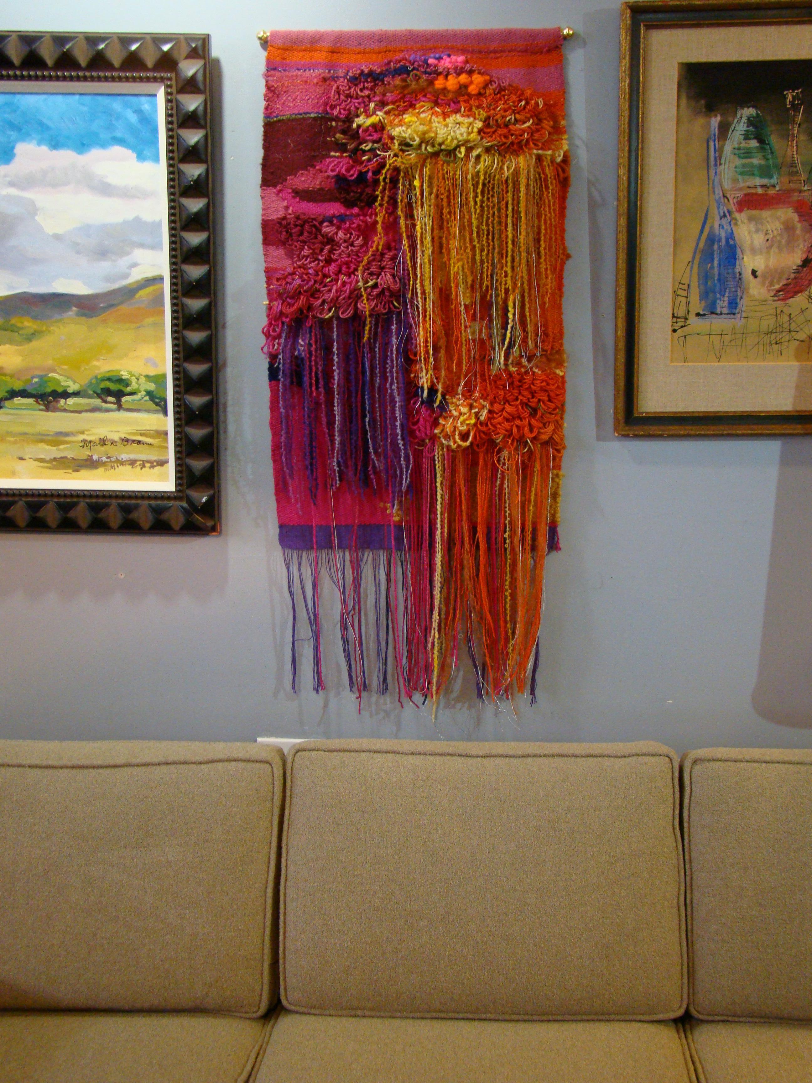A brilliant abstract composition of raveled yarn art, hand-loomed in a range of oranges, grape and fuchsia. Likely created in the 1970s, signed with the artists label, these works are often under-appreciated and represent tremendous skill, artistry,