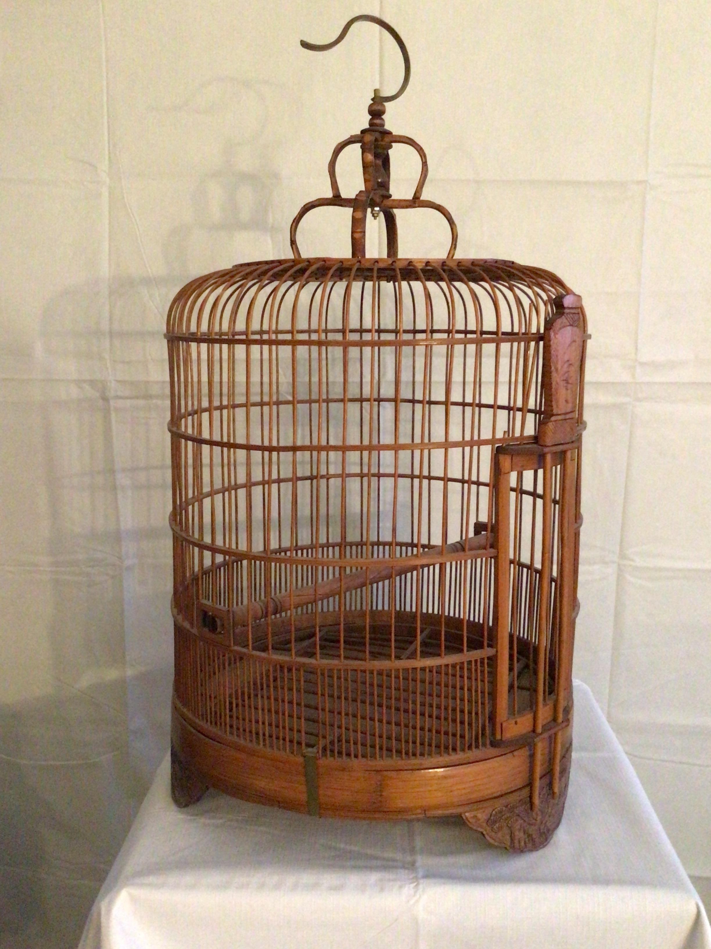 1960s Handmade Bamboo Wood Birdcage With Brass Hook 
The bottom is held on by hooks to the top and they are removable. 
Legs have carving of birds
Height is to top of hook