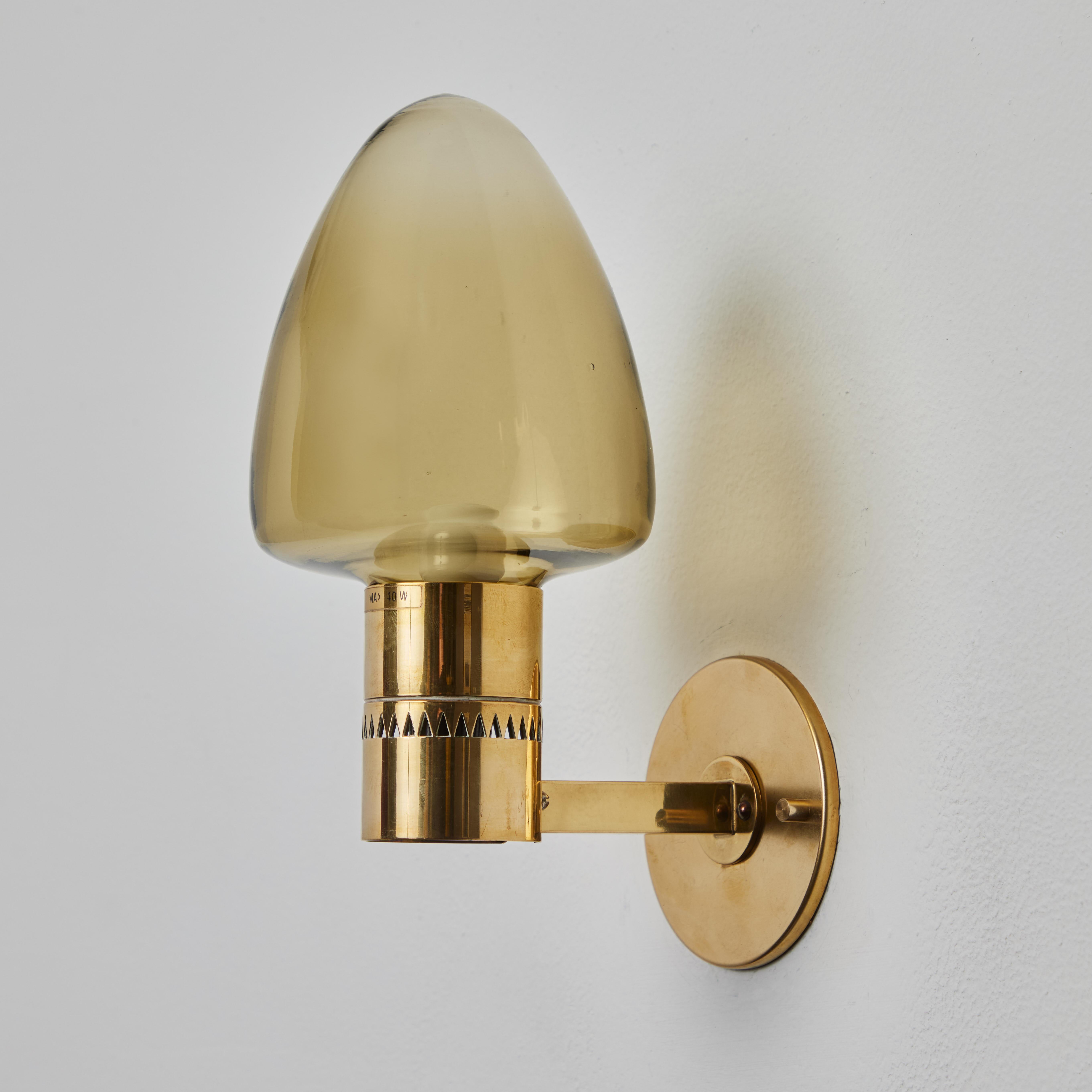 1960s Hans-Agne Jakobsson Model V-220 Brass & Glass Sconce for Markaryd. An incredibly refined vintage design that is quintessentially Swedish. Executed in sculpturally bent brass and blown smoked glass.

Price is per item. 3 lamps