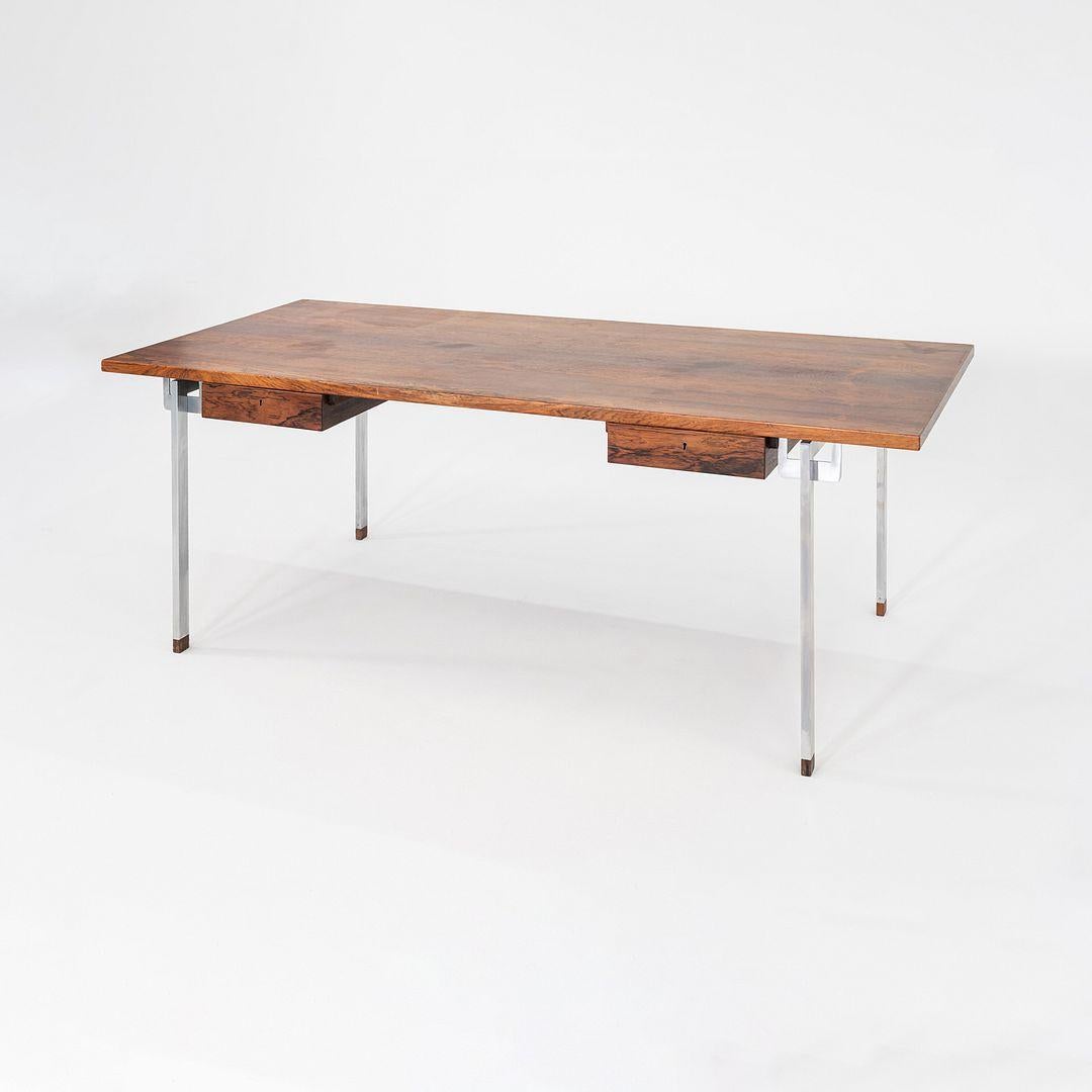Il s'agit d'un bureau en bois de rose et en acier, modèle AT 325, conçu par Hans J. Wegner pour Andreas Tuck au Danemark en 1960. Cet exemple a été exécuté avec un plateau en bois de rose et deux tiroirs peu profonds verrouillables sous le plateau.