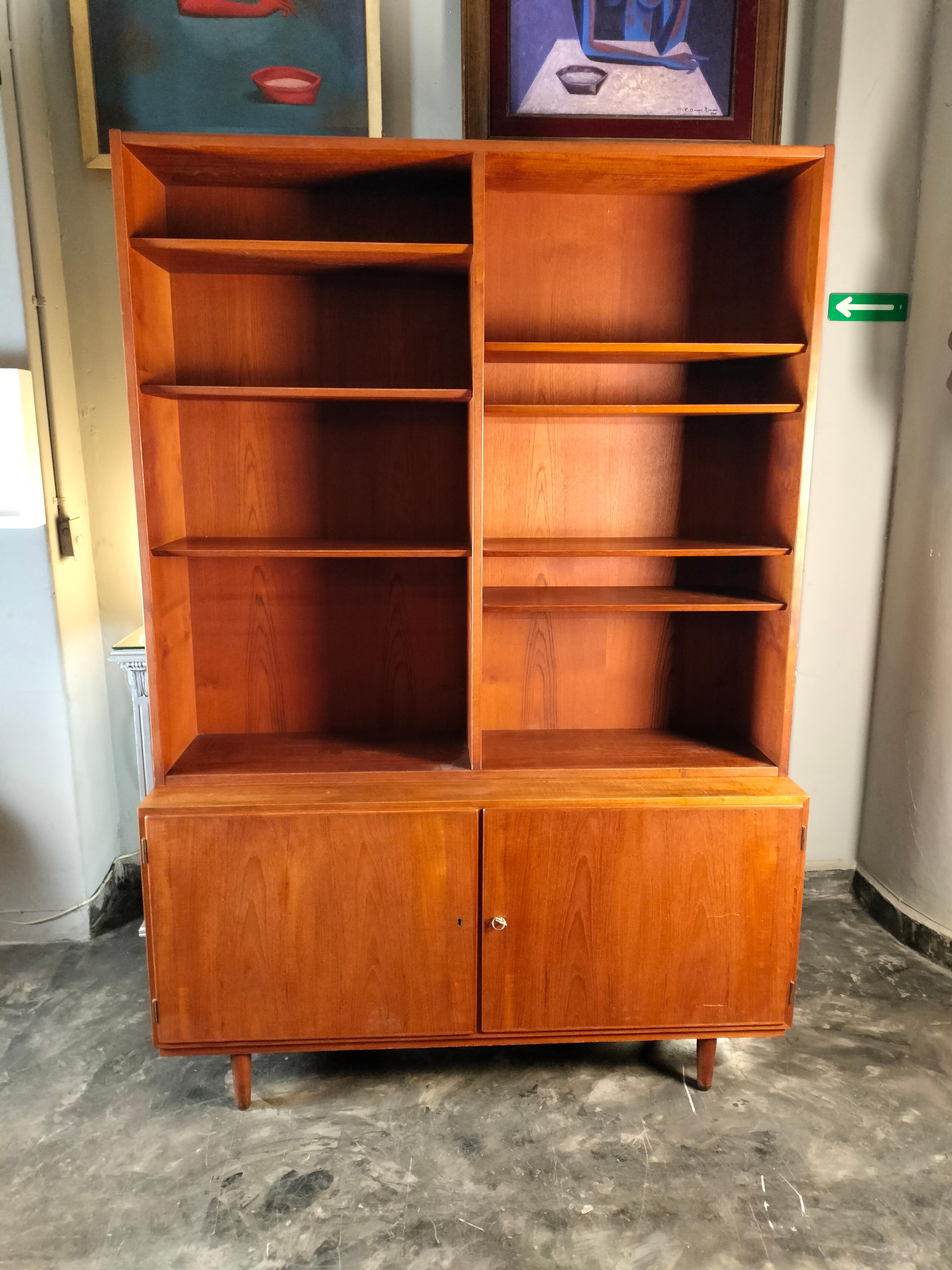 Bibliothèque à deux niveaux en bois de teck de Hans Olsen, datant des années 1960. Le niveau inférieur comporte 2 portes, 3 tiroirs intérieurs à gauche (2 avec tissu vert) et une étagère à droite. Le niveau supérieur comporte 7 étagères. Les deux