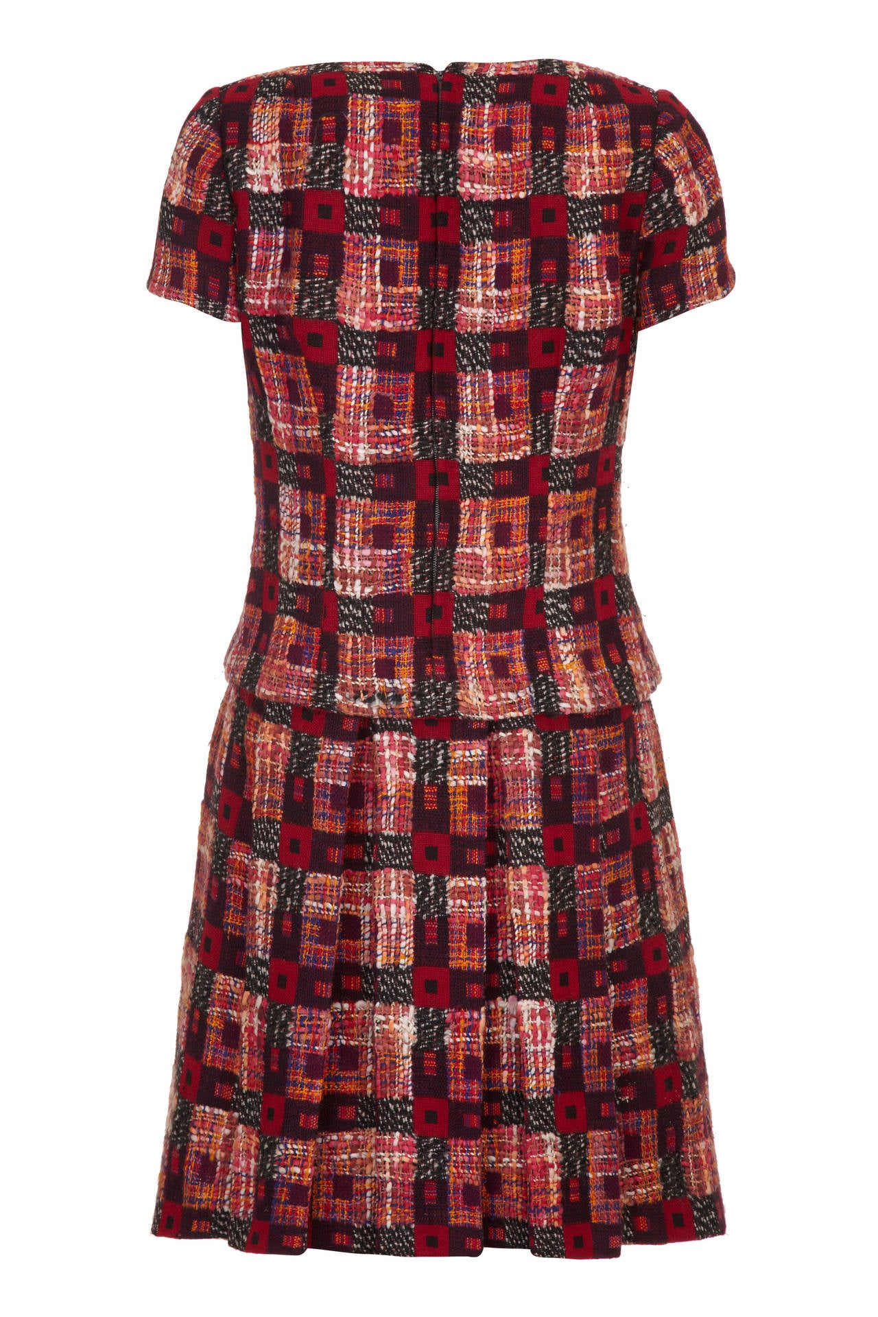 This charming 1960s fantasy wool tweed dress from Harrods in tones of deep red, russet and brown has the appearance of separates but is in fact one piece with a playful box pleat skirt attached to the lining of the bodice. It features short sleeves,