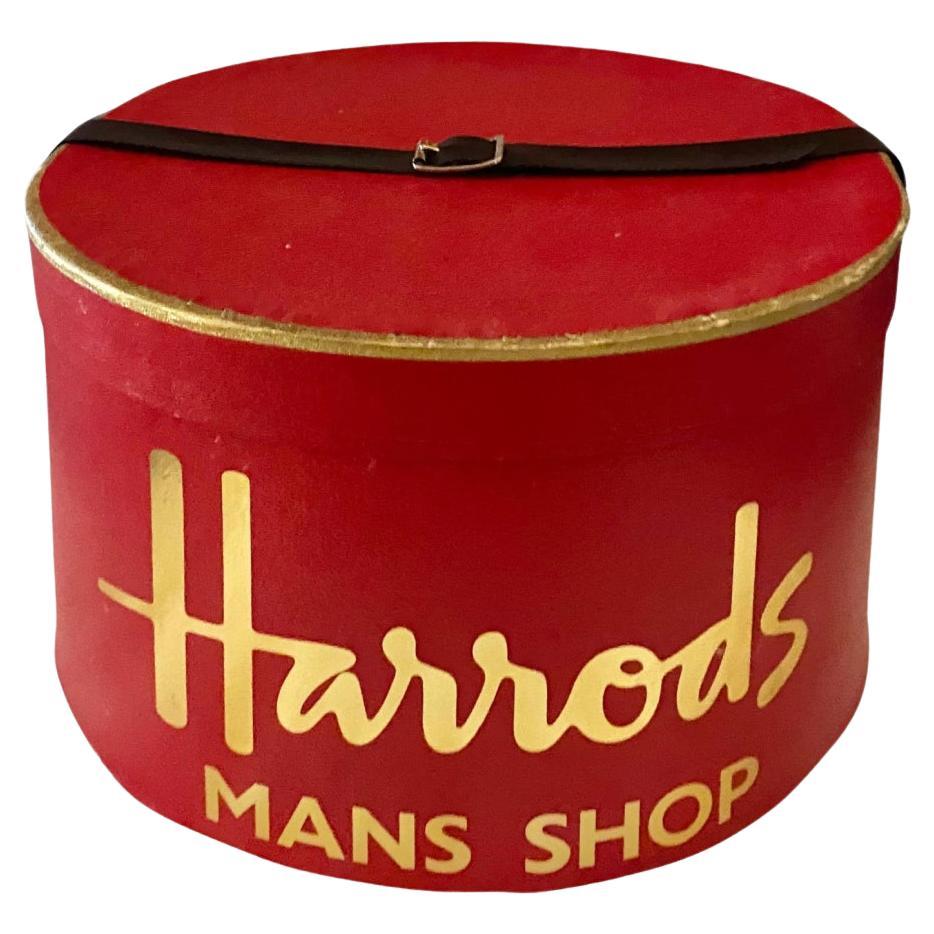 Elevate your style with the 1960s Harrods Hat Box, meticulously crafted from red cardboard and adorned with a luxurious leather handle on the lid. This exclusive piece from the prestigious luxury brand is a must-have for any discerning individual,