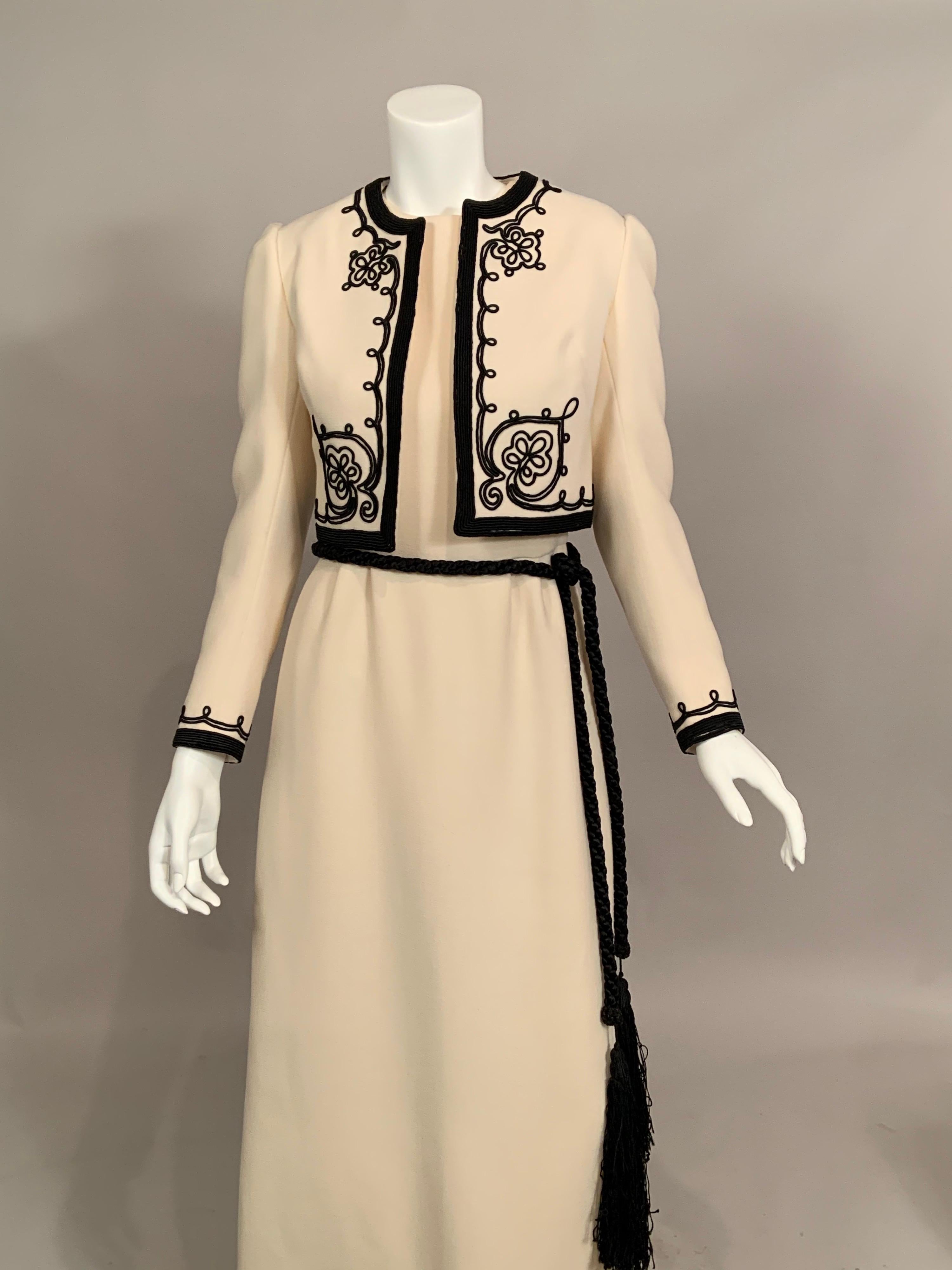 Cream wool is accented by black silk soutache on this evening dress and jacket deigned by Harry Algo in Paris for the Julius Garfinckel Department Store in Washington, D.C. in the 1960's.  The sleeveless dress has a round neckline, Armholes trimmed