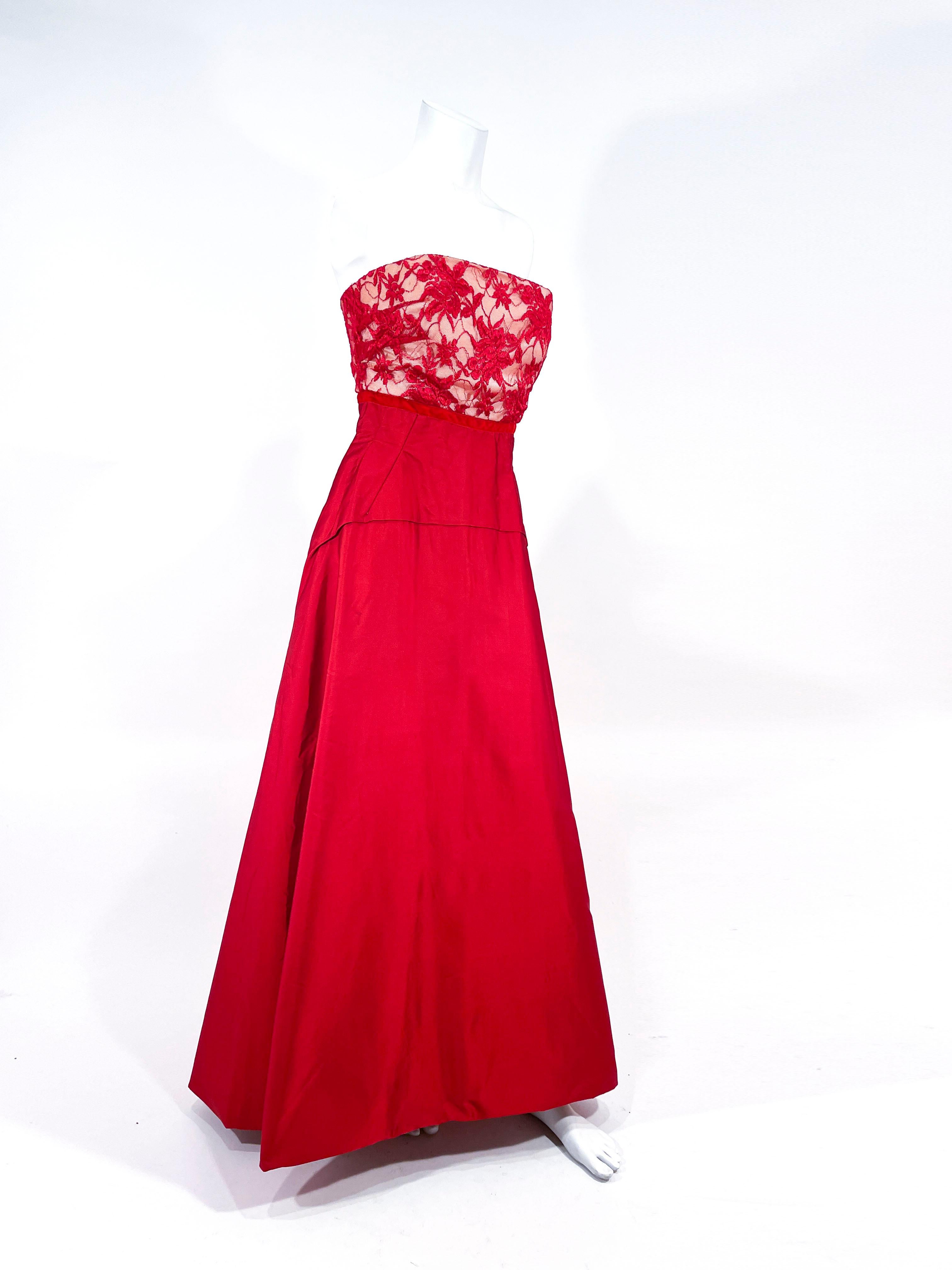 1960s Red duchess stain evening gown with a strapless bodice in a matching red illusion lace. The empire waistline has a red velvet trim and the skirt is entirely faced to give the skirt body and a structured shape. The back has a metal zippered