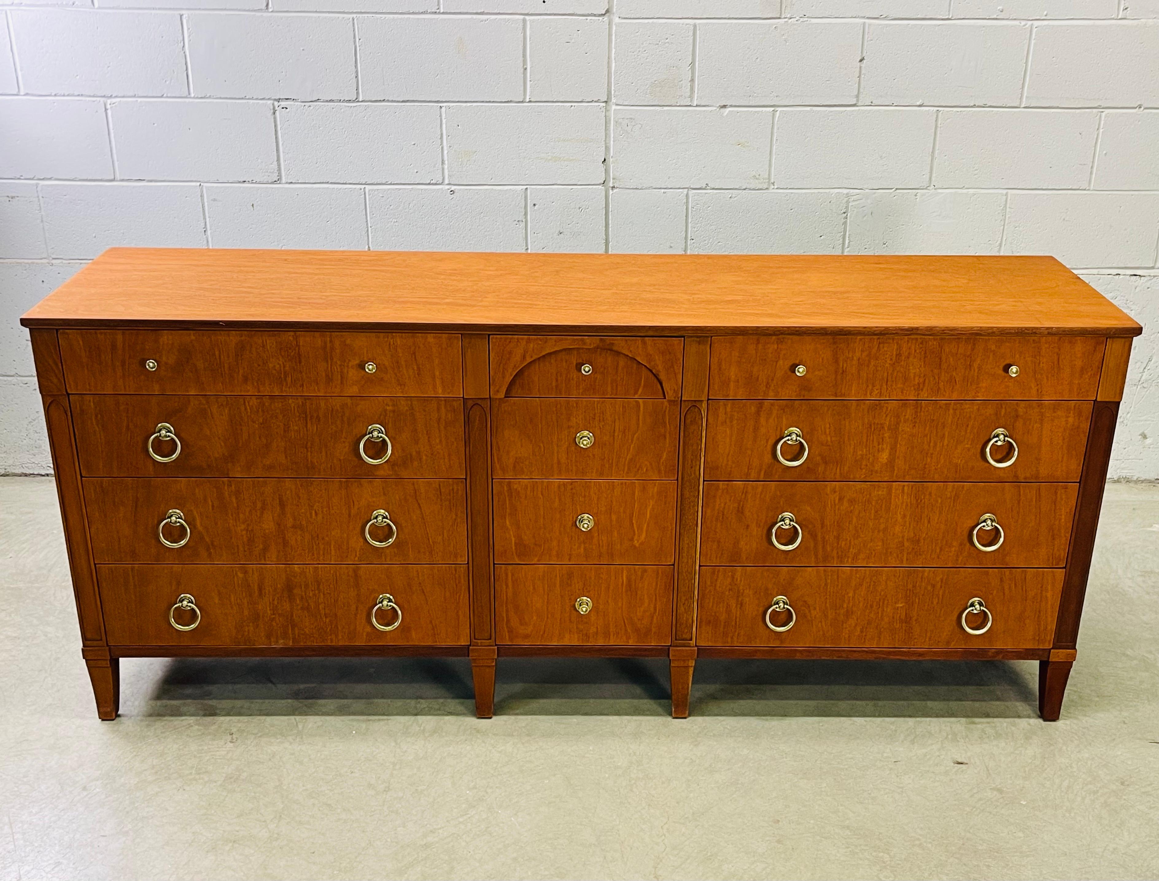 Vintage 1960s cherry wood twelve drawer low dresser with an arch design by Henredon Furniture Company. The dresser has round brass pulls. The drawers are 3-5.5”H for ample storage. The dresser is in newly refinished condition. Marked.