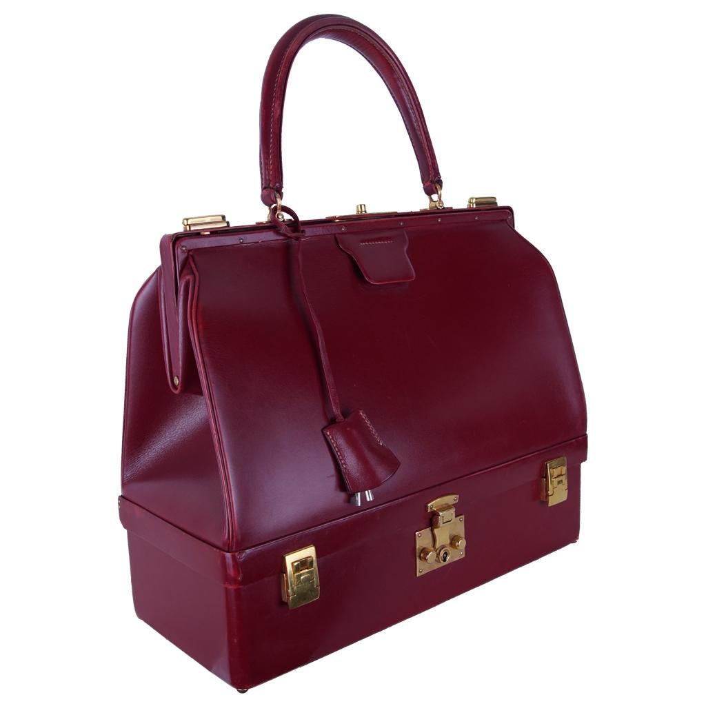 1960s Hermès Bourgundy Sac Mallette Handbag with Jewel Compartment. It was used by wealthy women to travel. The upper part has the function of a classic bag, the lower part is a compartment for jewelry. Includes 2 velvet cookers also from Hermes.