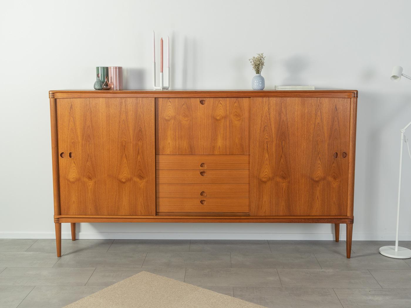 Classic highboard from the 1960s. High quality corpus in teak veneer with two sliding doors, four drawers, a hinged compartment, seven shelves and cigar shaped feet.

Quality Features:

    accomplished design: perfect proportions and recognizable
