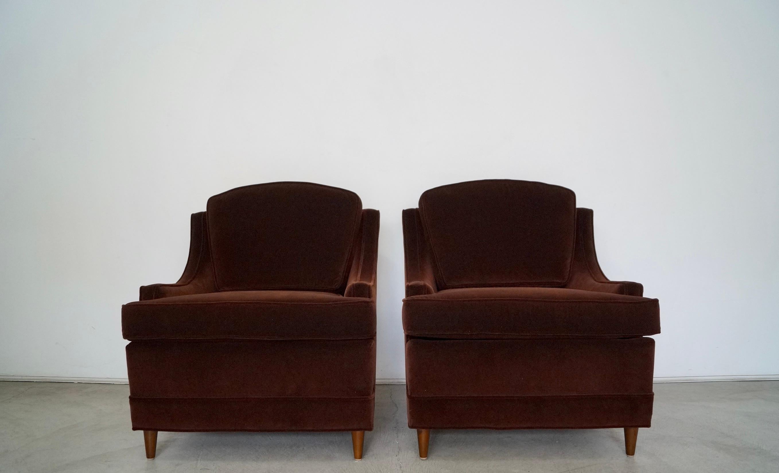 Vintage pair of Mid-Century Modern lounge chairs for sale. The chairs have been professionally reupholstered in a high-quality deep dark chocolate brown velvet and new foam. They have an elegant Hollywood Regency design with sloping arms and tapered