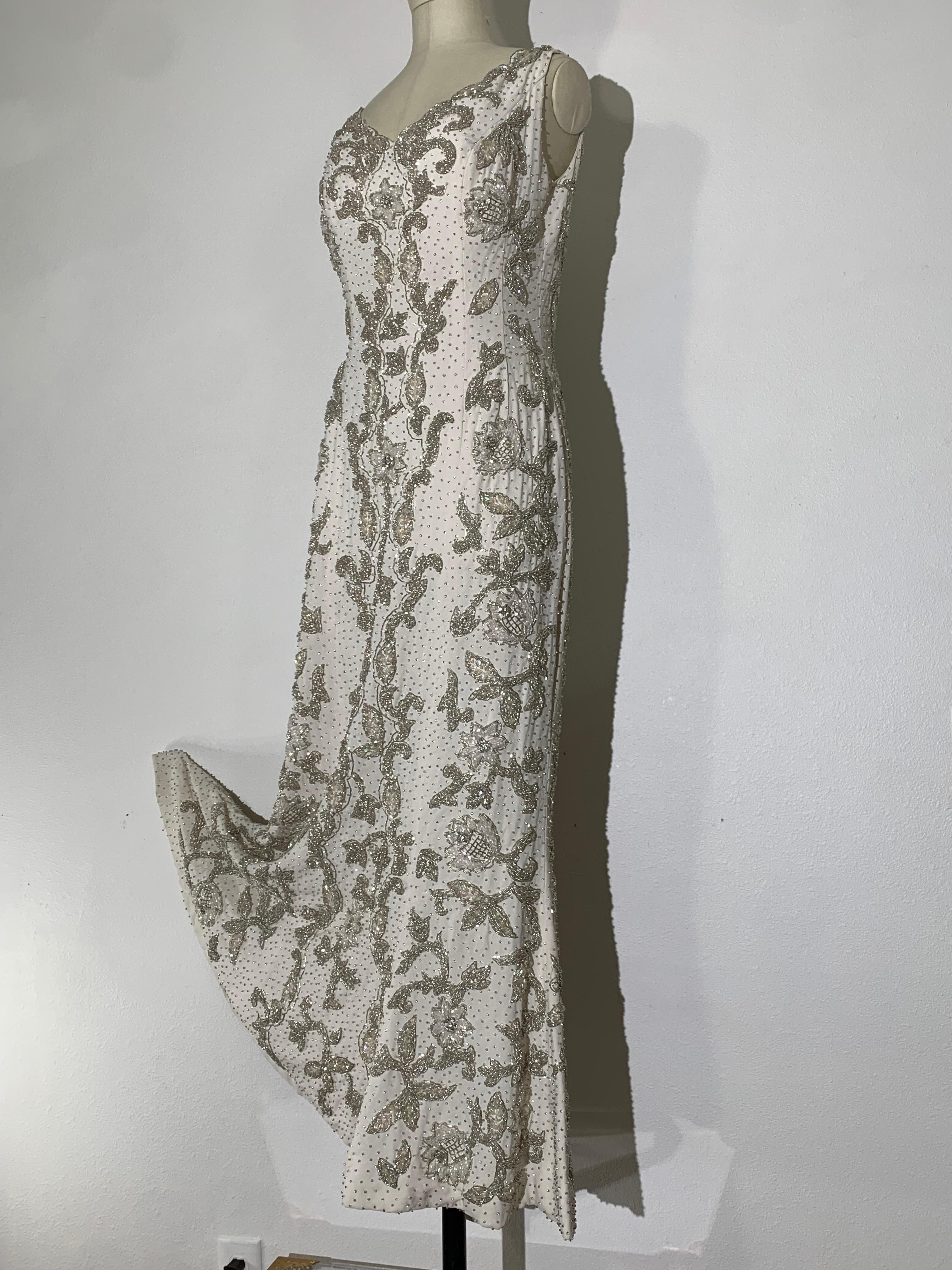 1960s Hong Kong Beaded White Silk Crepe Fishtail Wedding Gown: A mint condition, curvaceous and body affirming sleeveless gown made by the best beadwork of its era in silver encrusted floral motif. Full fishtail hemline with lots of movement will