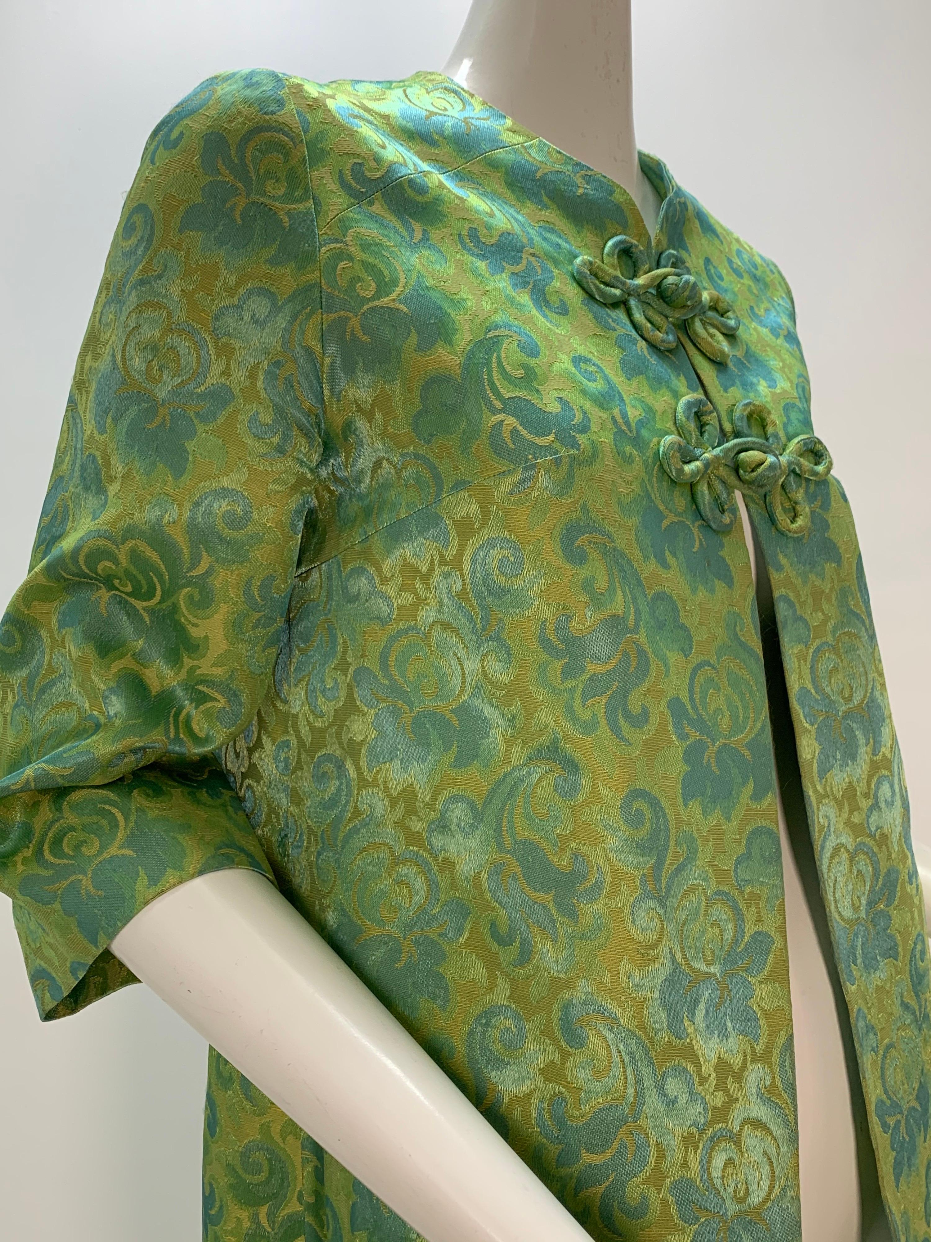 A 1960s green and aqua brocade jacket: Collarless Hong Kong-styled with 2 piped frog closures at neckline and 3/4 length sleeves. Lined. 