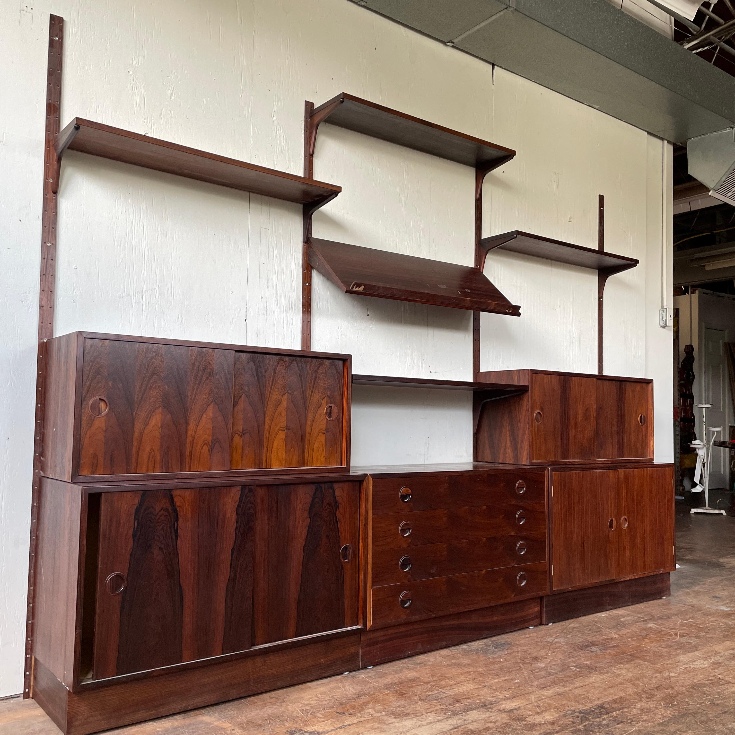 A gorgeous 1960s Hundevad modular wall unit in rosewood complete with shelves, brackets, case pieces, and even the original paper catalog. Set this unit up however best fits your home and enjoy the beauty and convenience of an authentic vintage wall