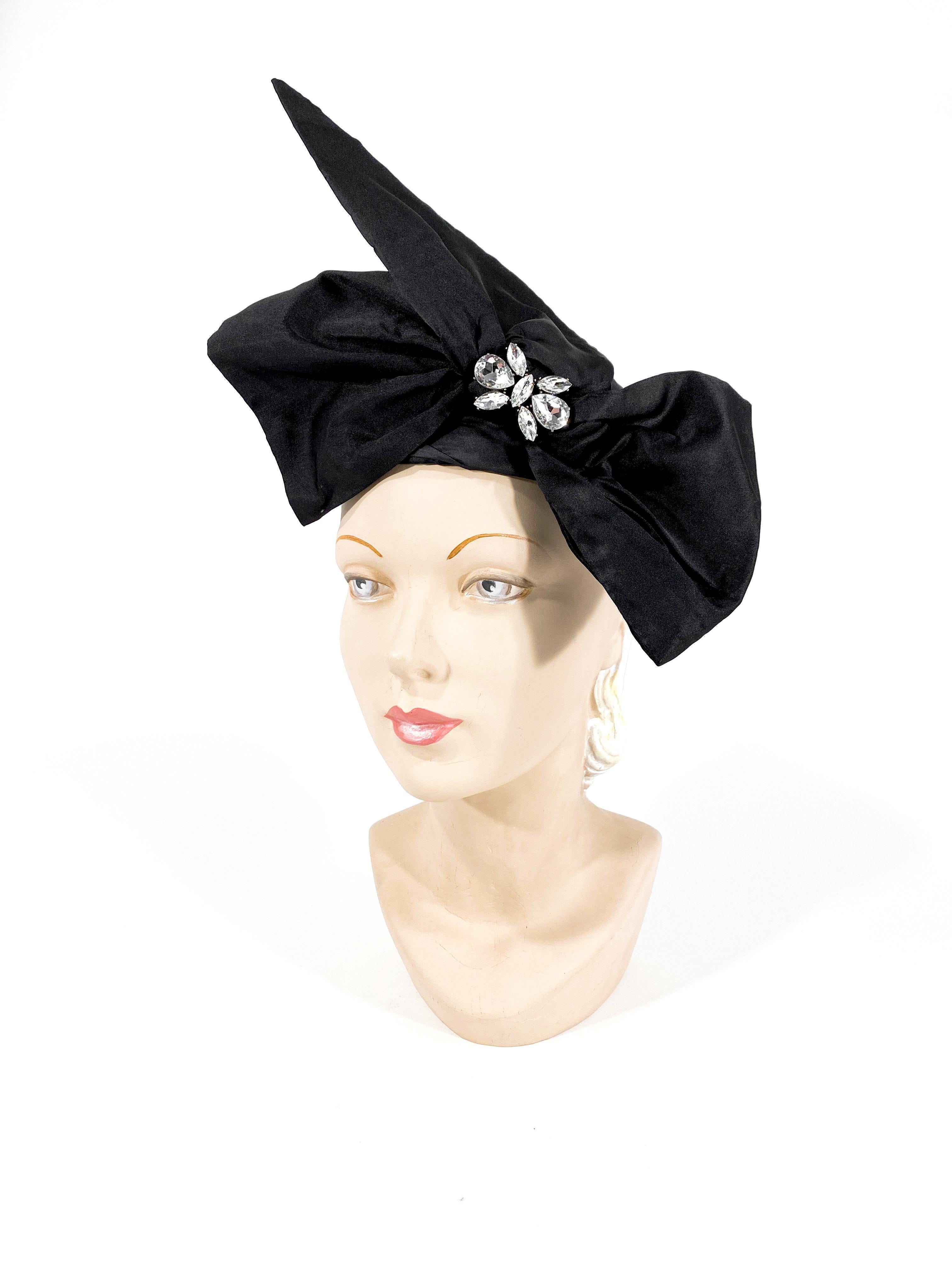 1960 black silk fashion pillbox hat with hand sculpted enlarged bow finished with a rhinestone accent. 