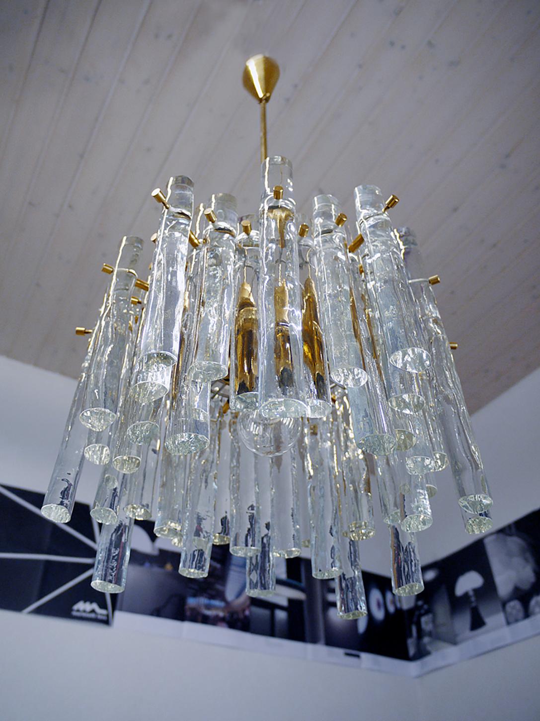Elegant chandelier with clear Murano glass rods of various lengths on a gilded brass metal frame. Hanging glass resembles icicles. Heavy duty. Chandelier illuminates beautifully and offers a lot of light. Gem from the time. With this light you make