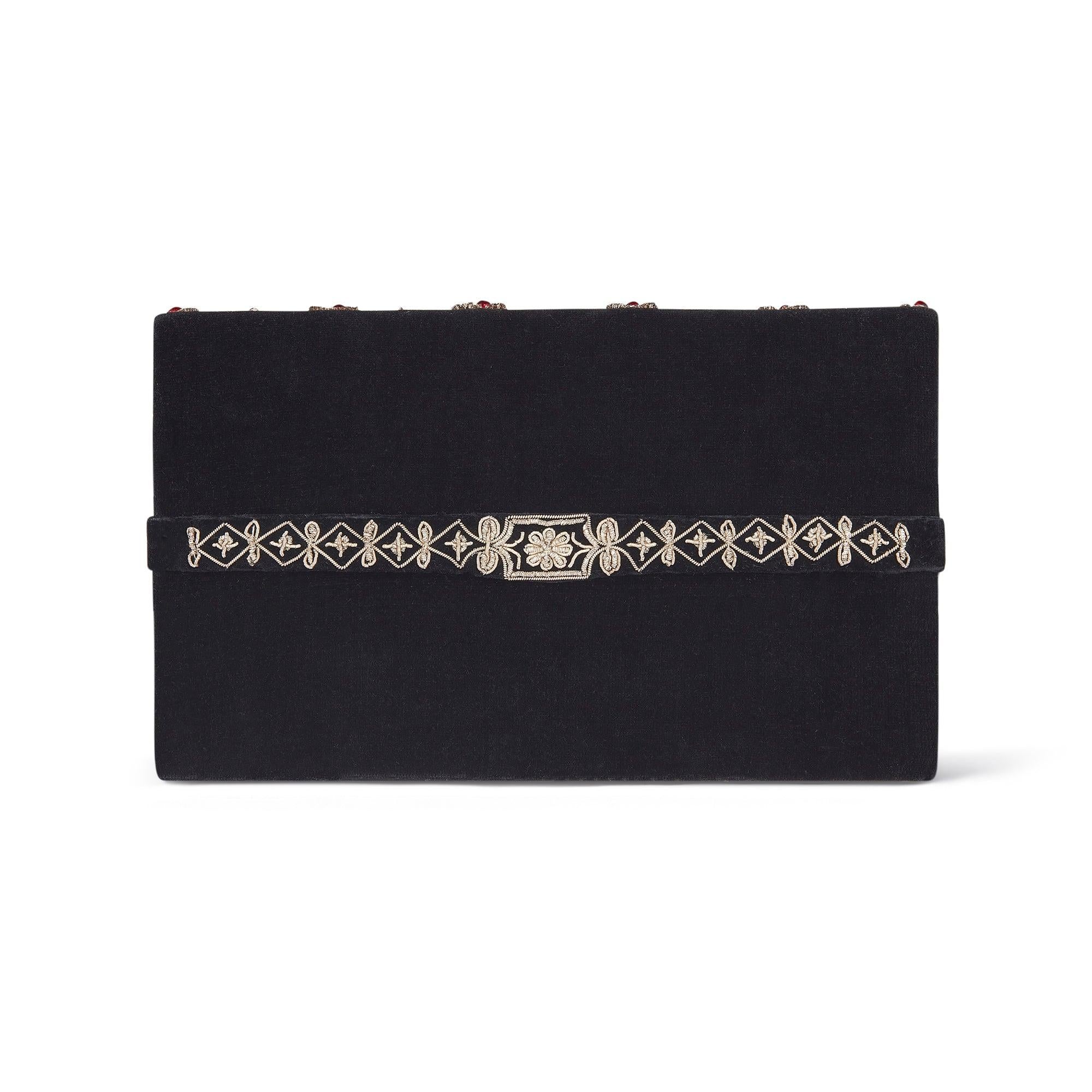 Diese Clutch Bag wurde Ende der 1950er bis Anfang der 1960er Jahre in Indien hergestellt. Sie ist außen aus schwarzem Samt gefertigt und hat eine Ziehharmonika-Konstruktion mit einem schwarzen Satinfutter. Das Innere enthält drei Fächer. Auf dem