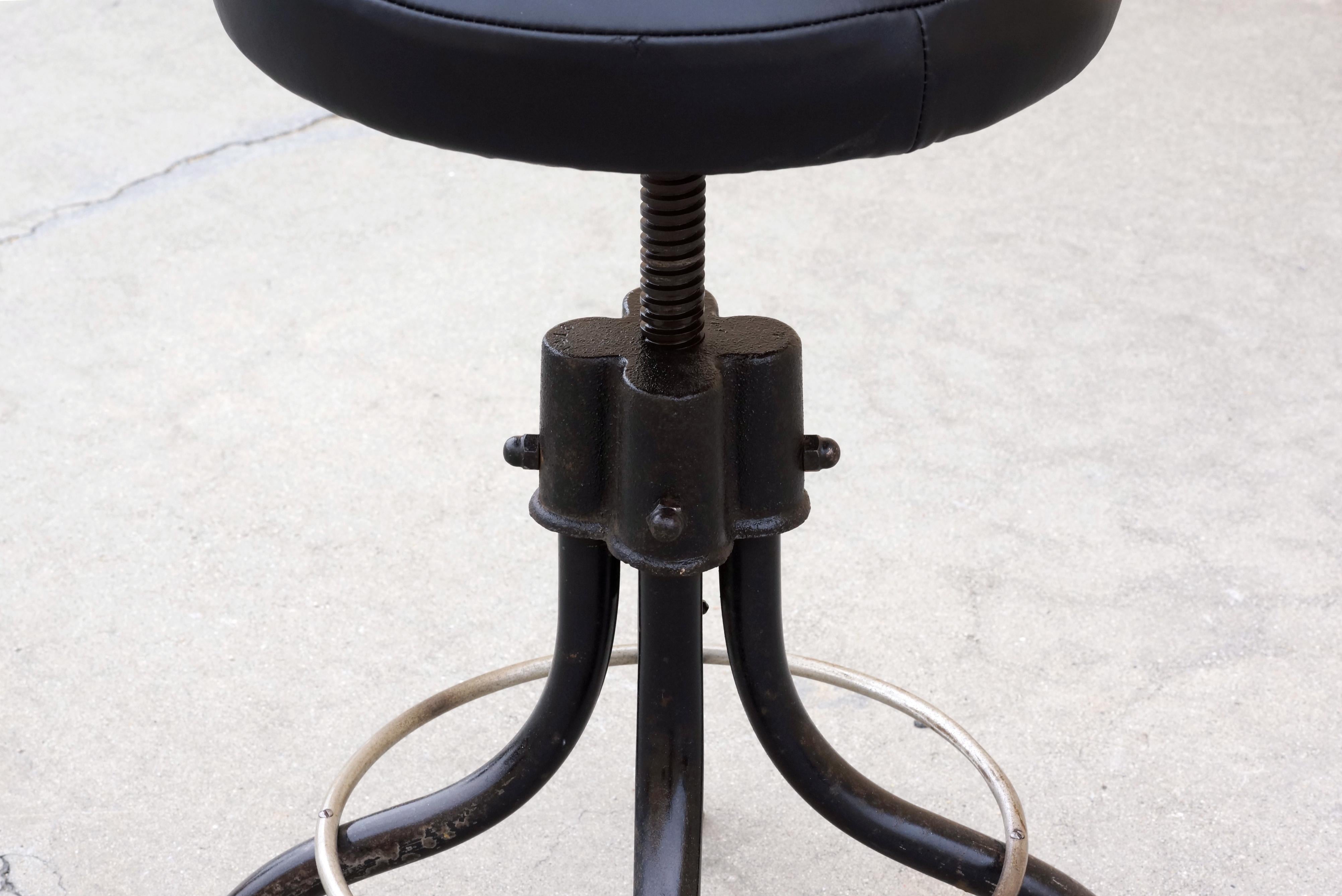 Machine Age shop stool with excellent vintage patina. Base has been lightly clear-coated to preserve its Industrial patina. Paired with a newly upholstered seat in black leather, circa 1940s.

Dimensions: 13