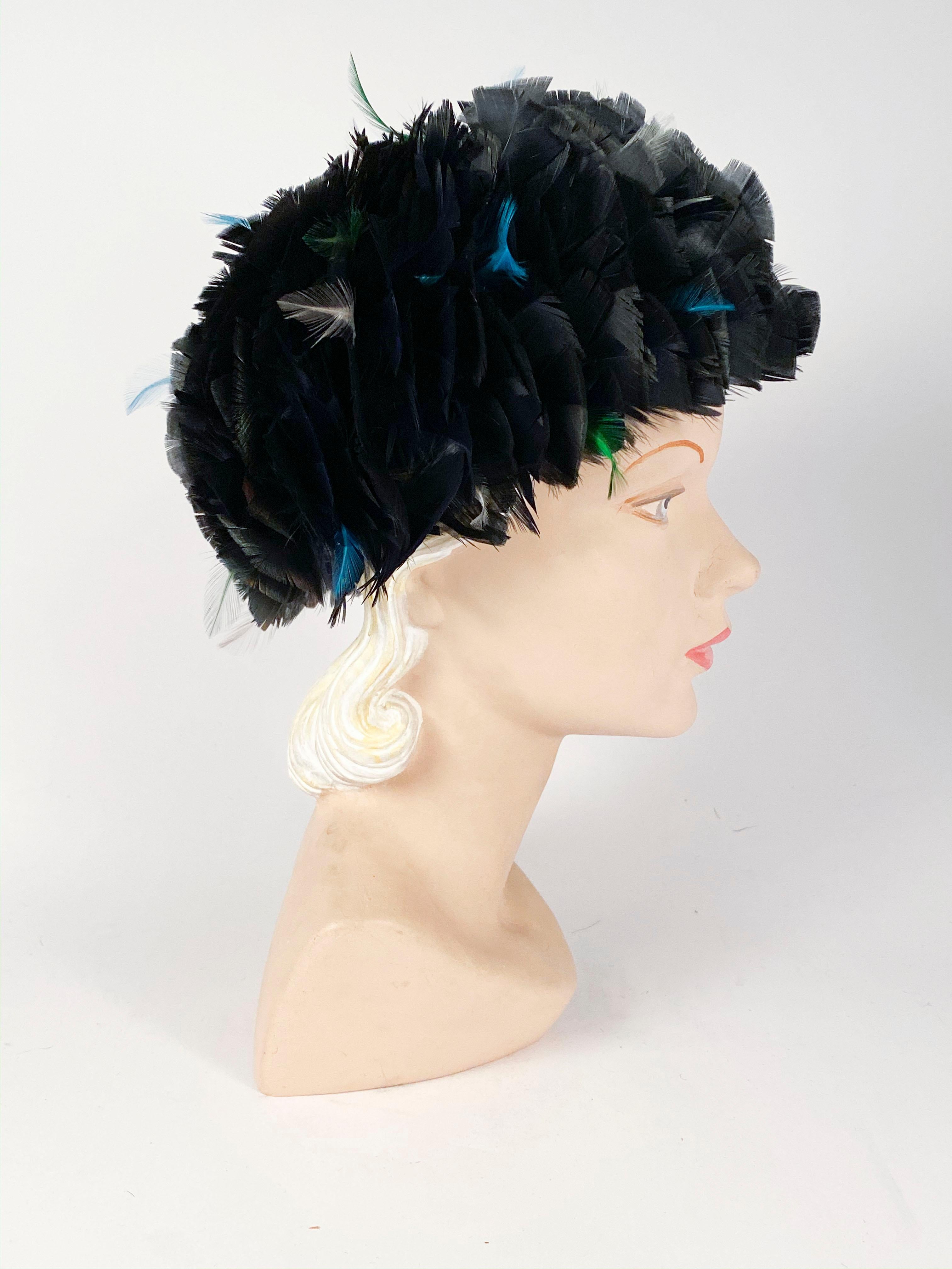 1960s Feathered hat encased in iridescent black feathers with a blue hue. There are also teal, cream, and green accent feathers along the field. The body is a blue structured lace with a wired brim.