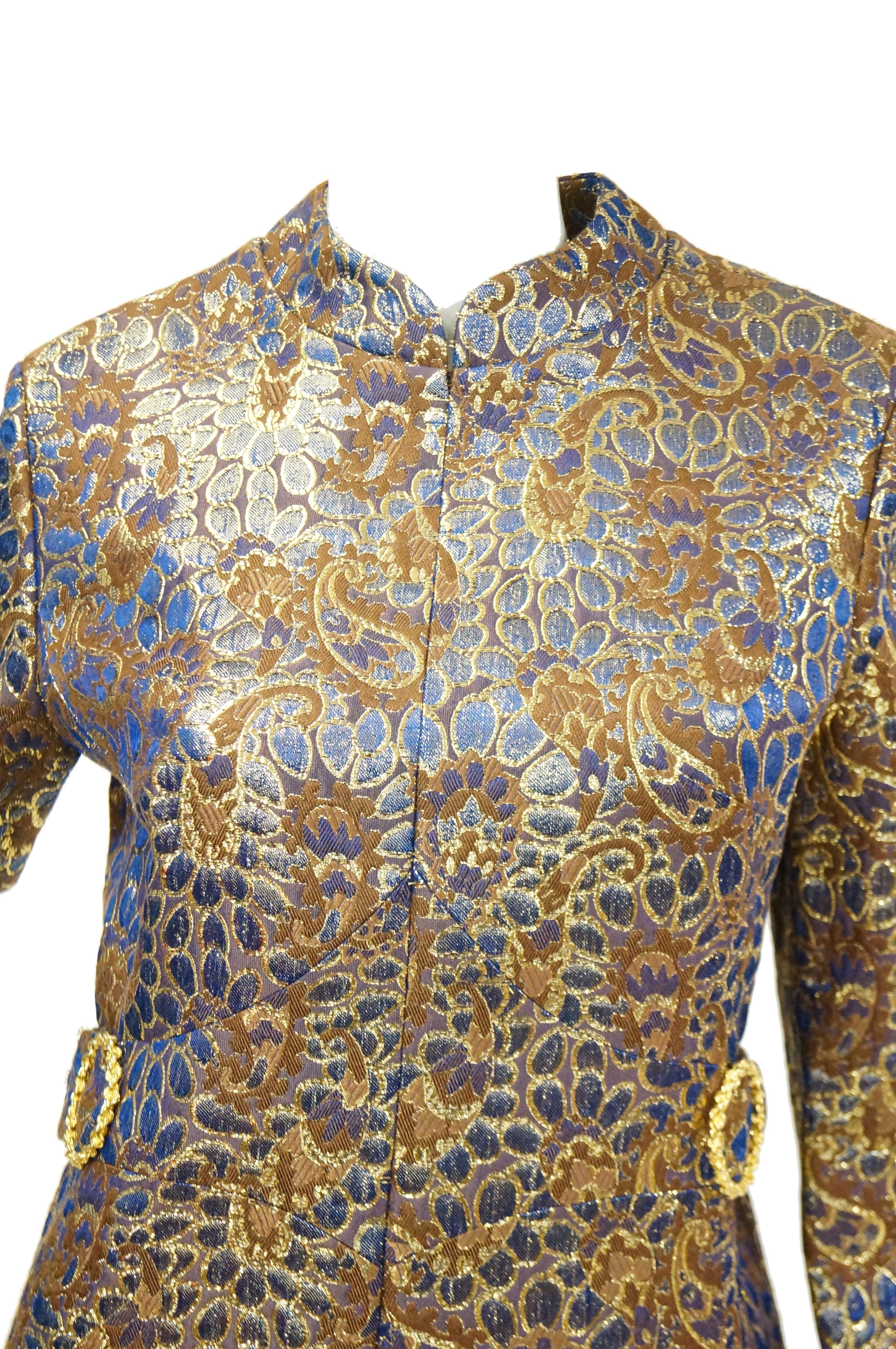 Incredible 1960s mod dress! This dress is knee length, with long sleeves, a notched faux - mandarin collar, and a fit - and - flare silhouette with bell - like skirt. Gold braided circular buckle details accent the narrow waist of the dress. The