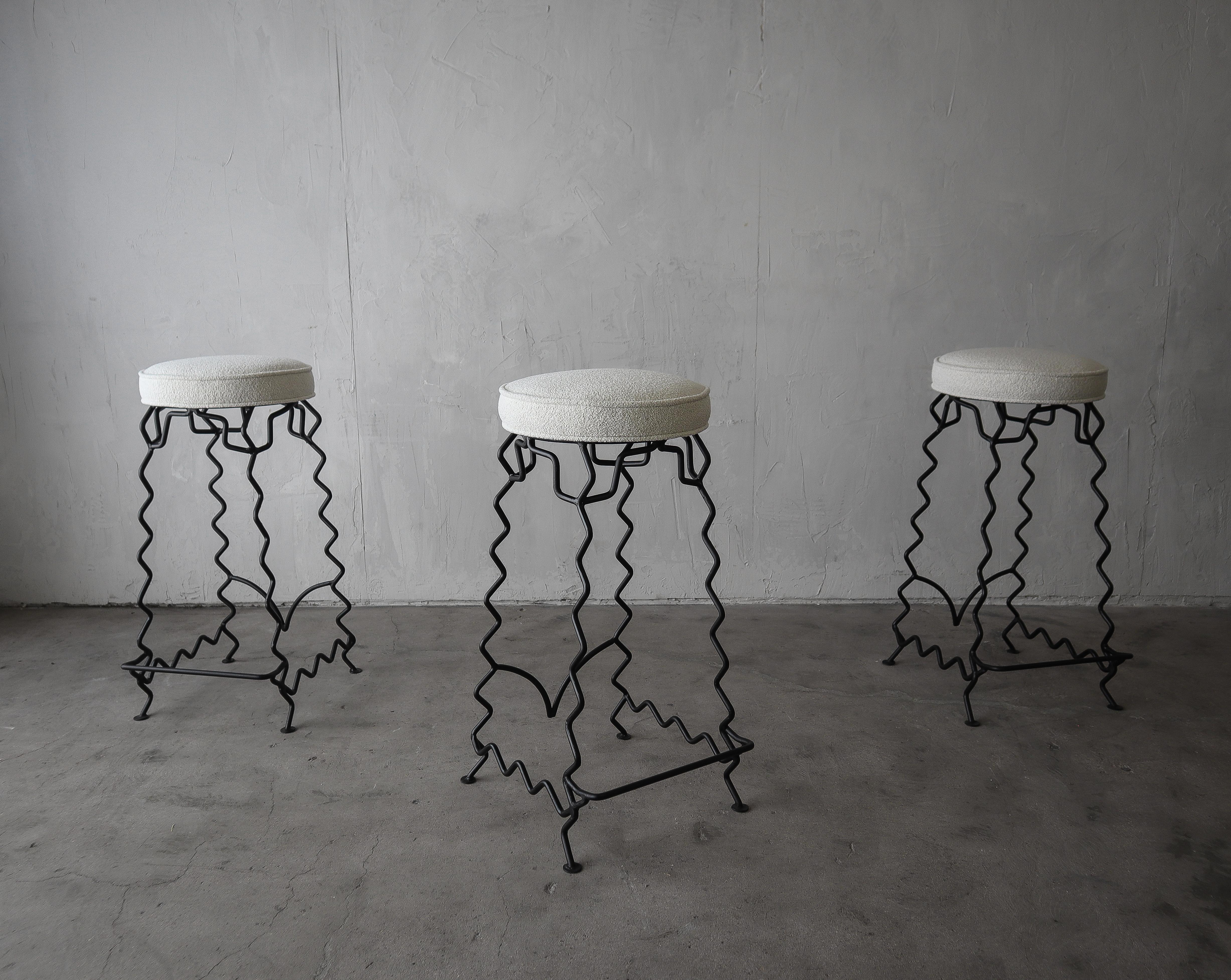 When art becomes furniture. Pictures do not do these unique and beautiful stools justice. These beautiful iron bar stools have been refreshed with all new black paint and foam and modernized with soft off white boucle fabric. These stools are the