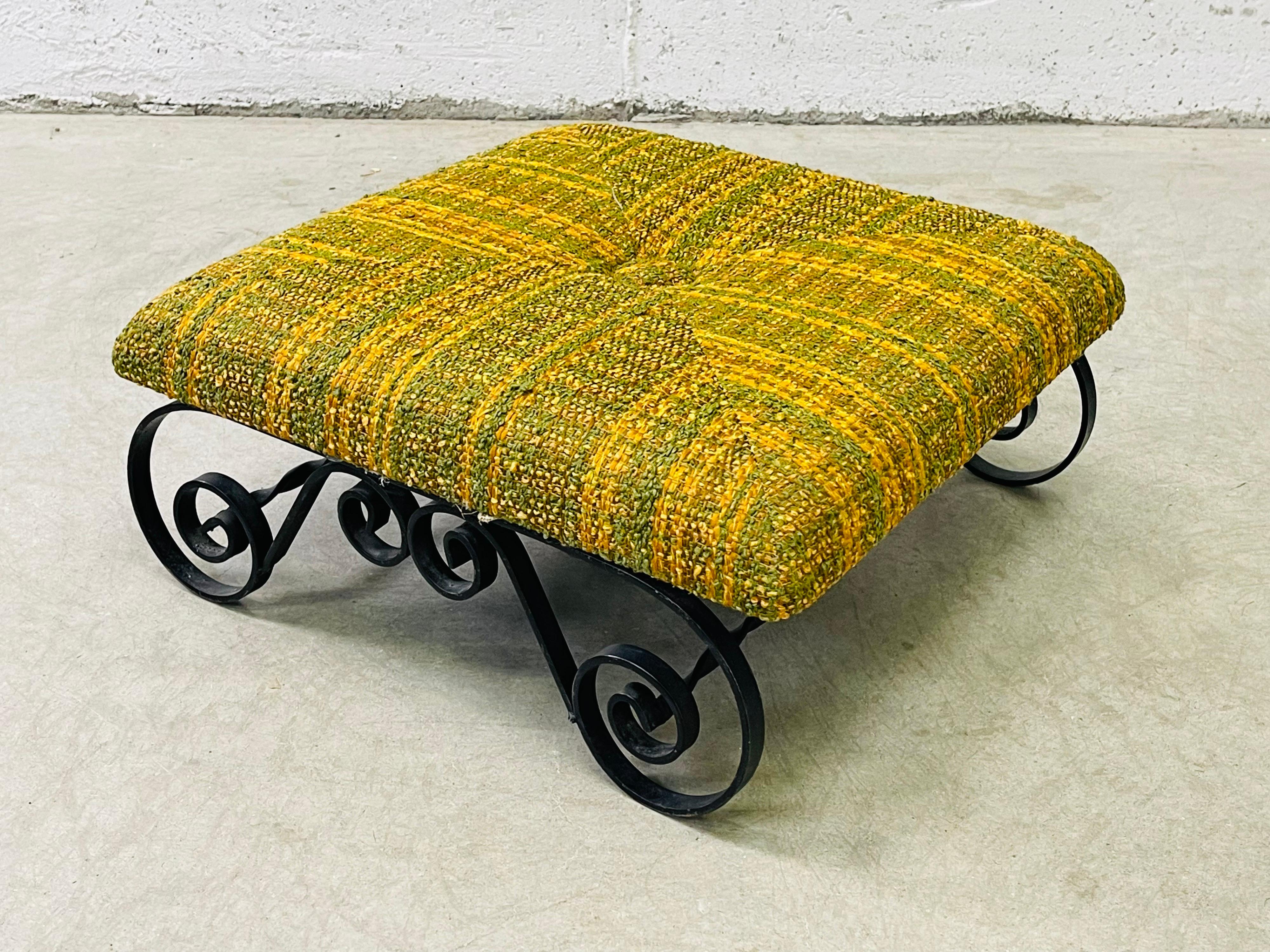 Vintage 1960s iron base and fabric top low footstool. The footstool has the original fabric with a button in the middle. Fabric is in very good condition. The wrought iron has a scroll design. No marks.