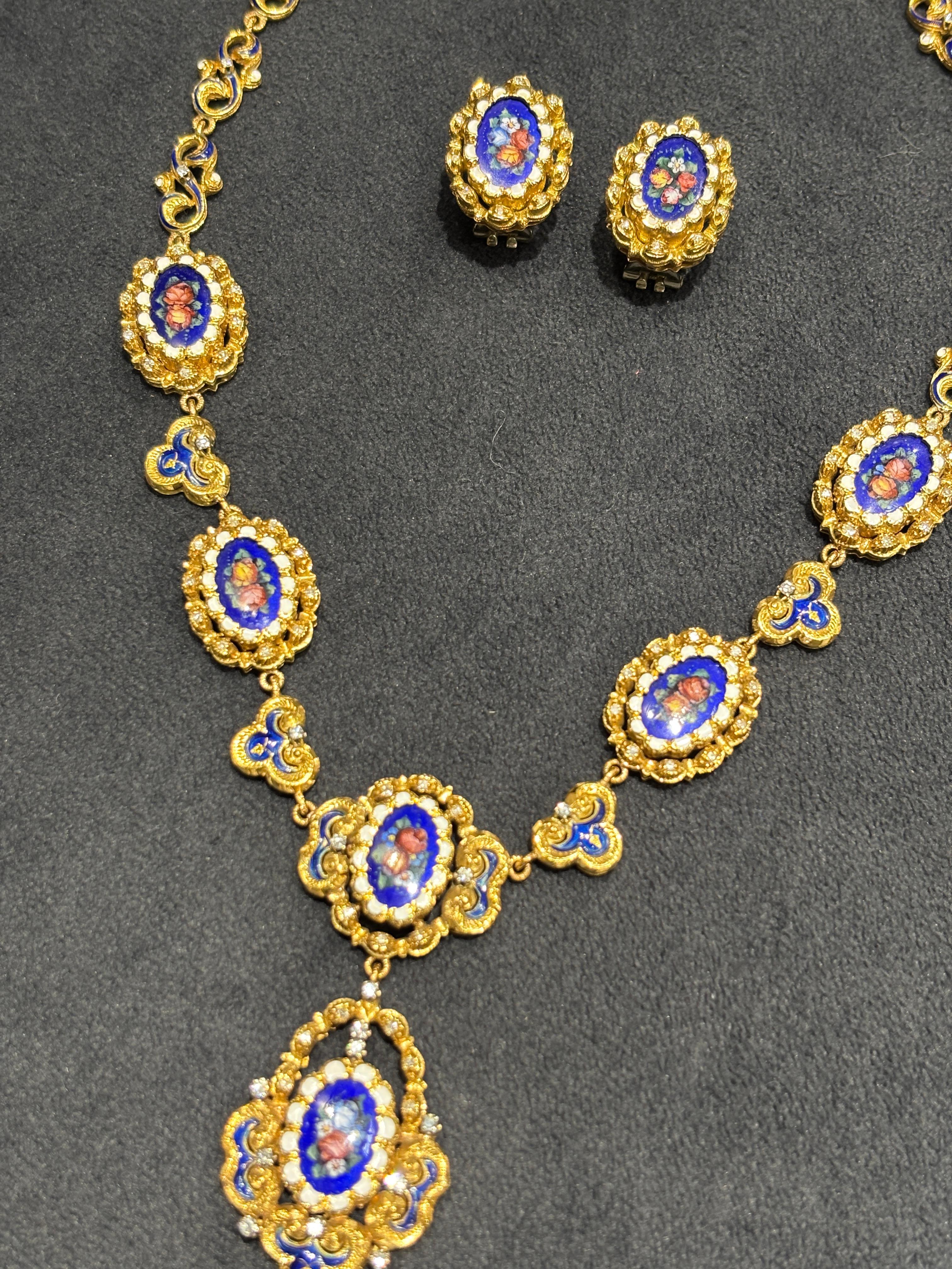 Questo intricato set di collana e orecchini in oro 18k italiano del 1960 è splendidamente ornato da vignette floreali smaltate. Ogni vignetta è ulteriormente impreziosita da piccoli diamanti a taglio rotondo. La lunghezza della collana è di 40 cm,