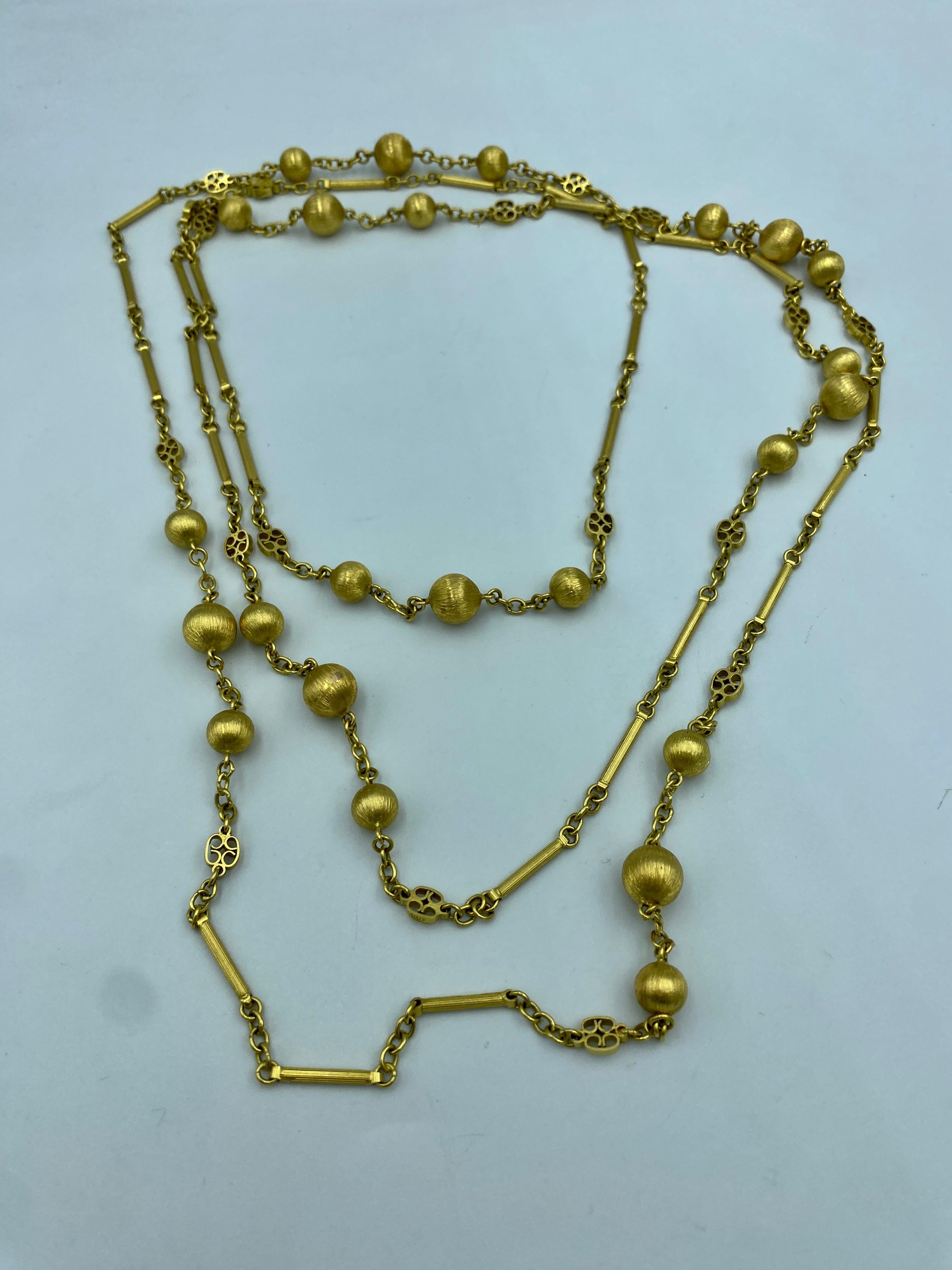The craftsmanship on this very long 18k gold necklace is quite remarkable. The chain is adorned with a repetition of balls and tubes all of which have been hand engraved to give them their texture. This chain is long enough to be worn as a 2,3 or 4