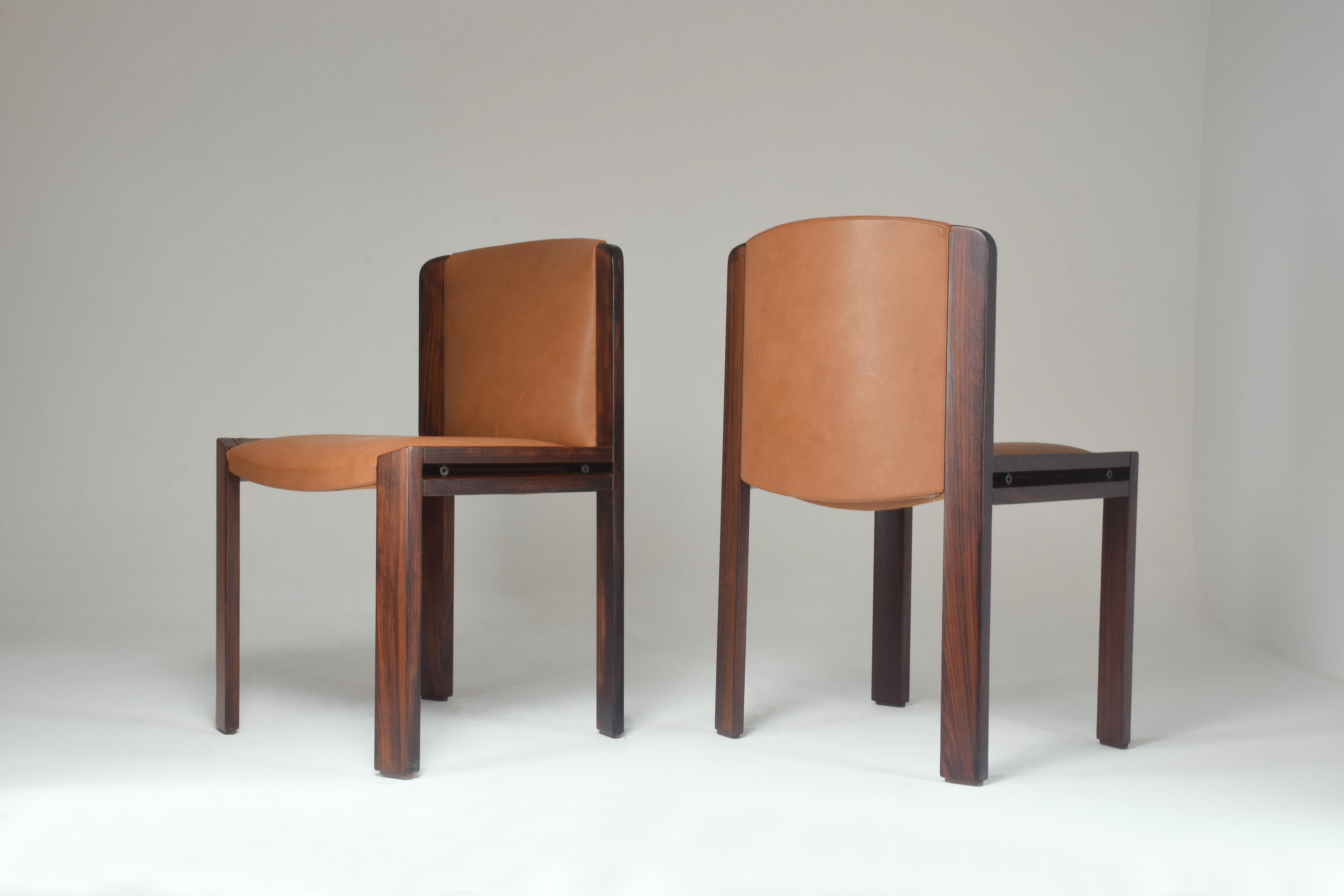 Two mid-20th-century chairs designed by Joe Colombo for Pozzi from the 1960's. These accent or side chairs stand out with their bold oak frame and beautifully carved slits on the sides. Impeccably restored by our team with new camel brown leather