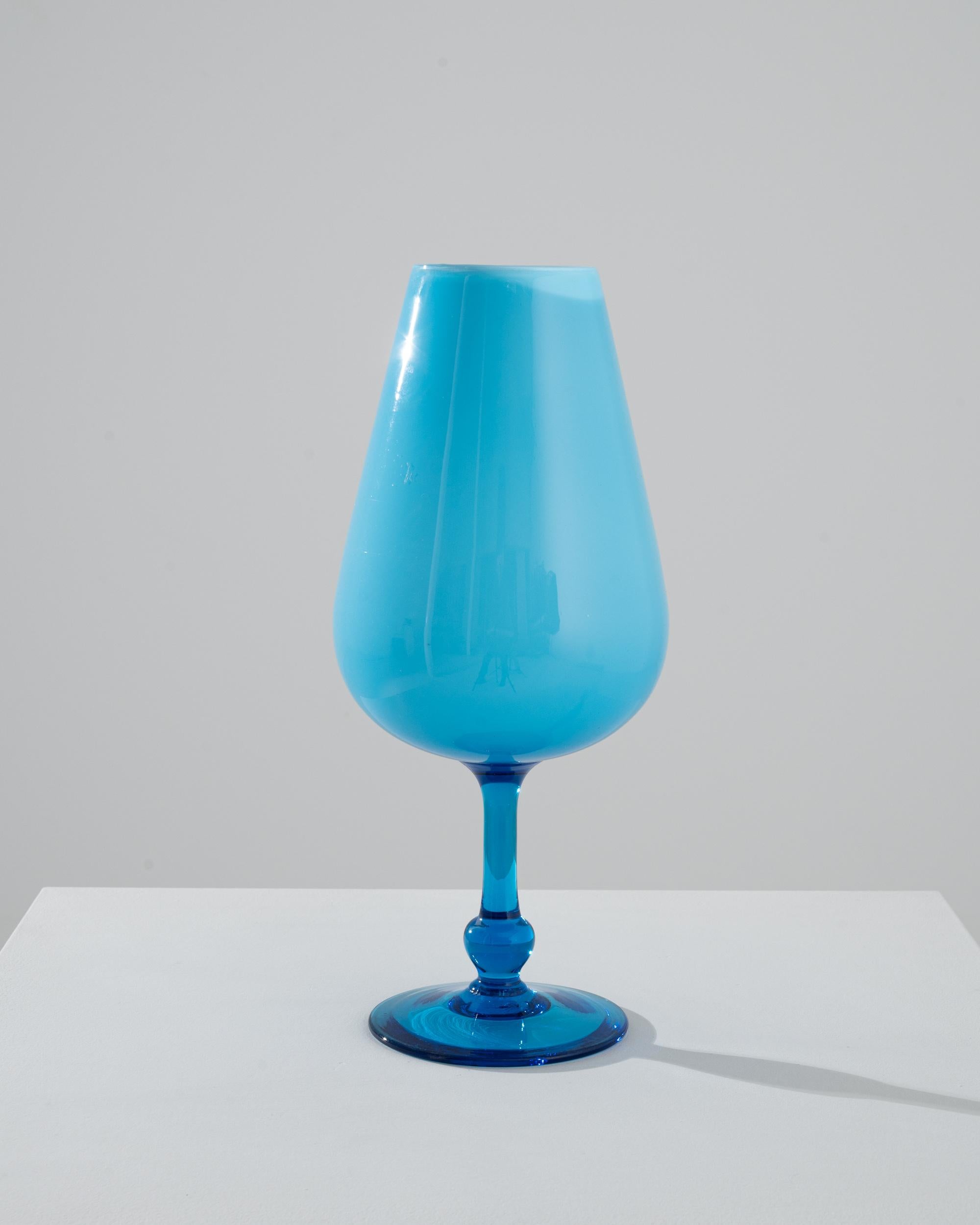 Romantic and striking, this glass goblet offers a unique vintage accent. Made in Italy in the 1960s, the shape is elegant and piercing: the articulated translucent blue foot gracefully merges with the opaque colored glass vessel. Beautifully