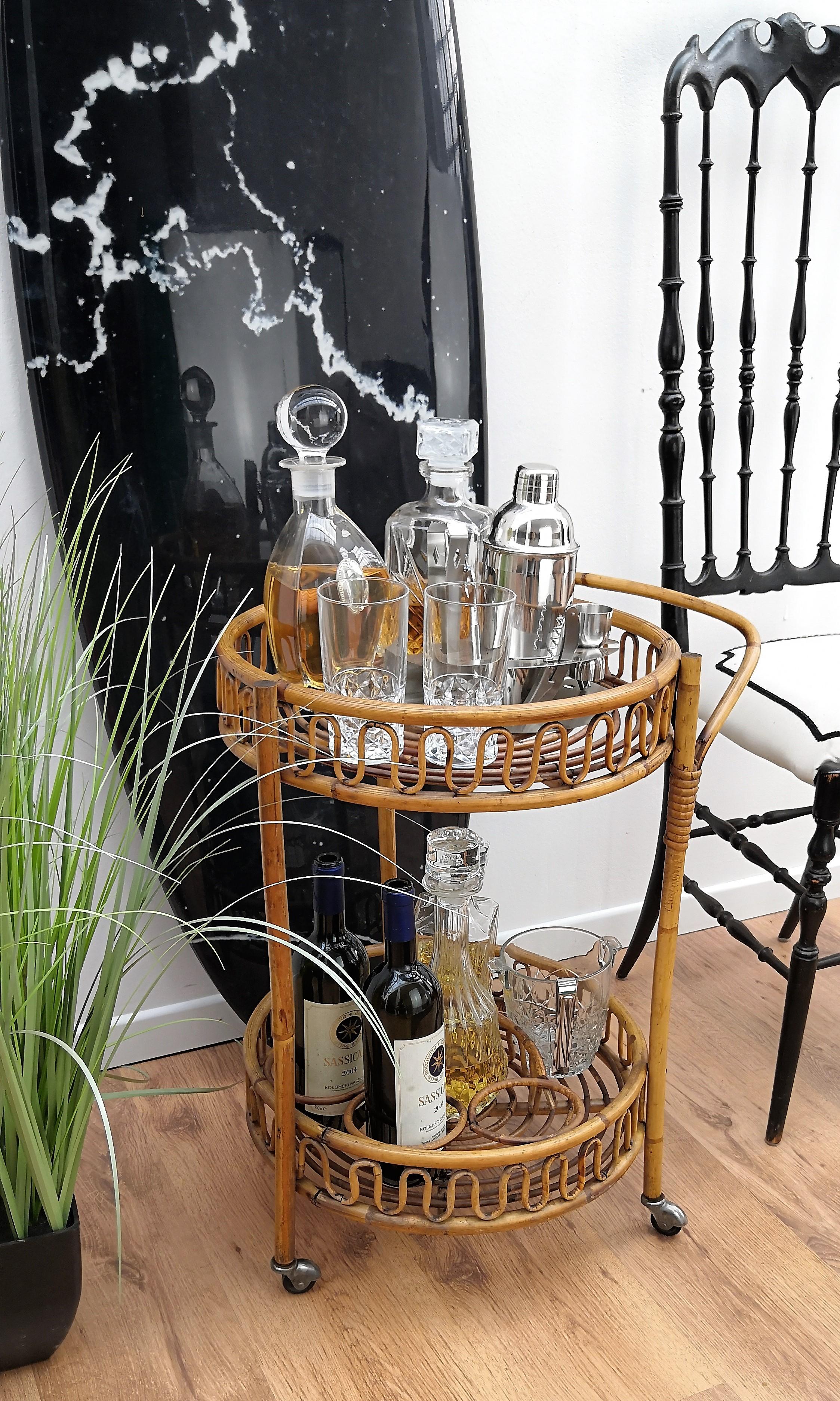 Beautiful 1960s Italian Mid-Century Modern Serving bar cart trolley probably by the Italian Vittorio Bonacina featuring two shelves, with the bottom one with three bottle holders. Made of rattan and bamboo. This charming piece is in the typical