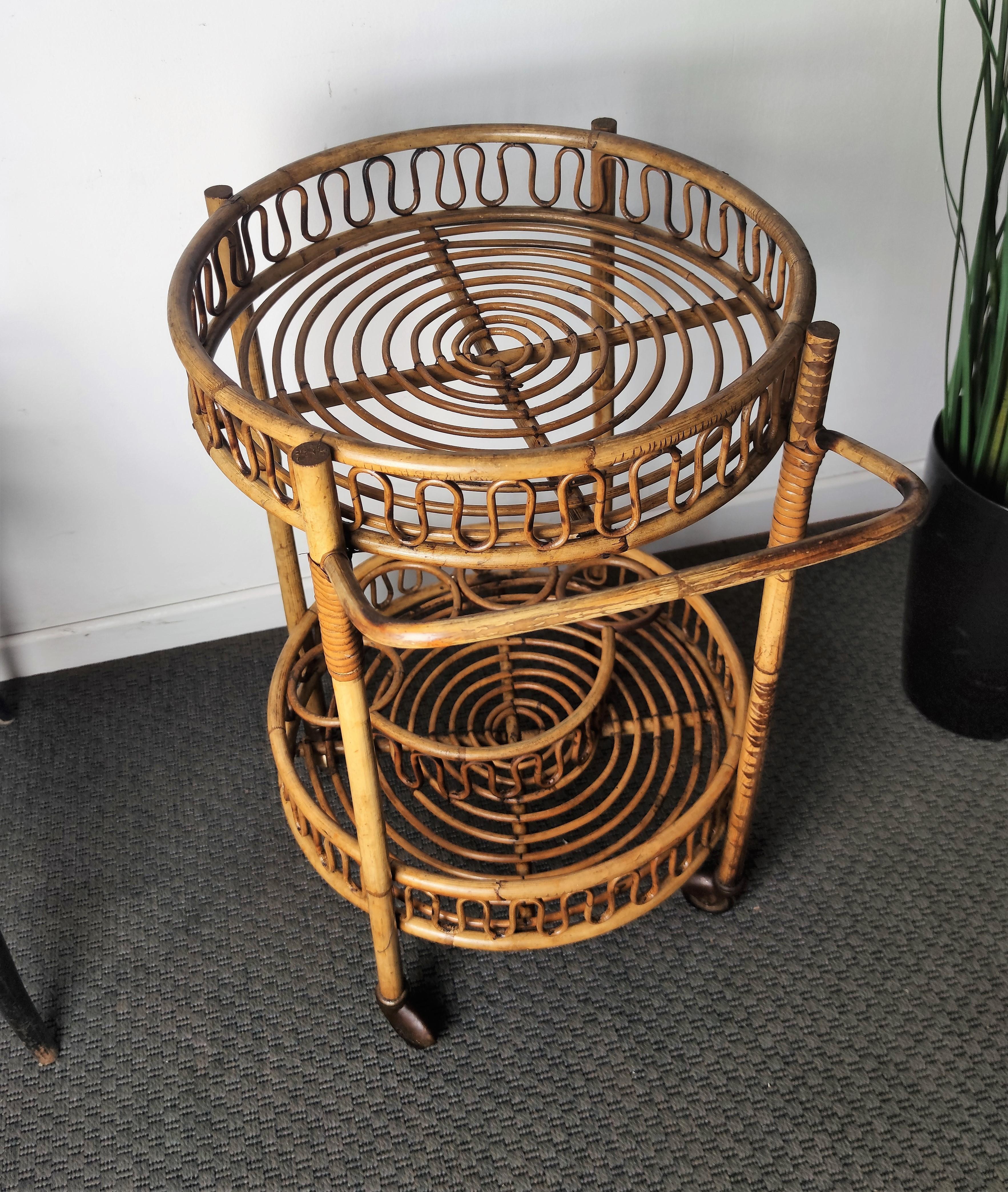 Beautiful 1960s Italian Mid-Century Modern serving bar cart trolley probably by the Italian Vittorio Bonacina featuring two shelves, with the bottom one with three bottle holders. Made of rattan and bamboo. This charming piece is in the typical