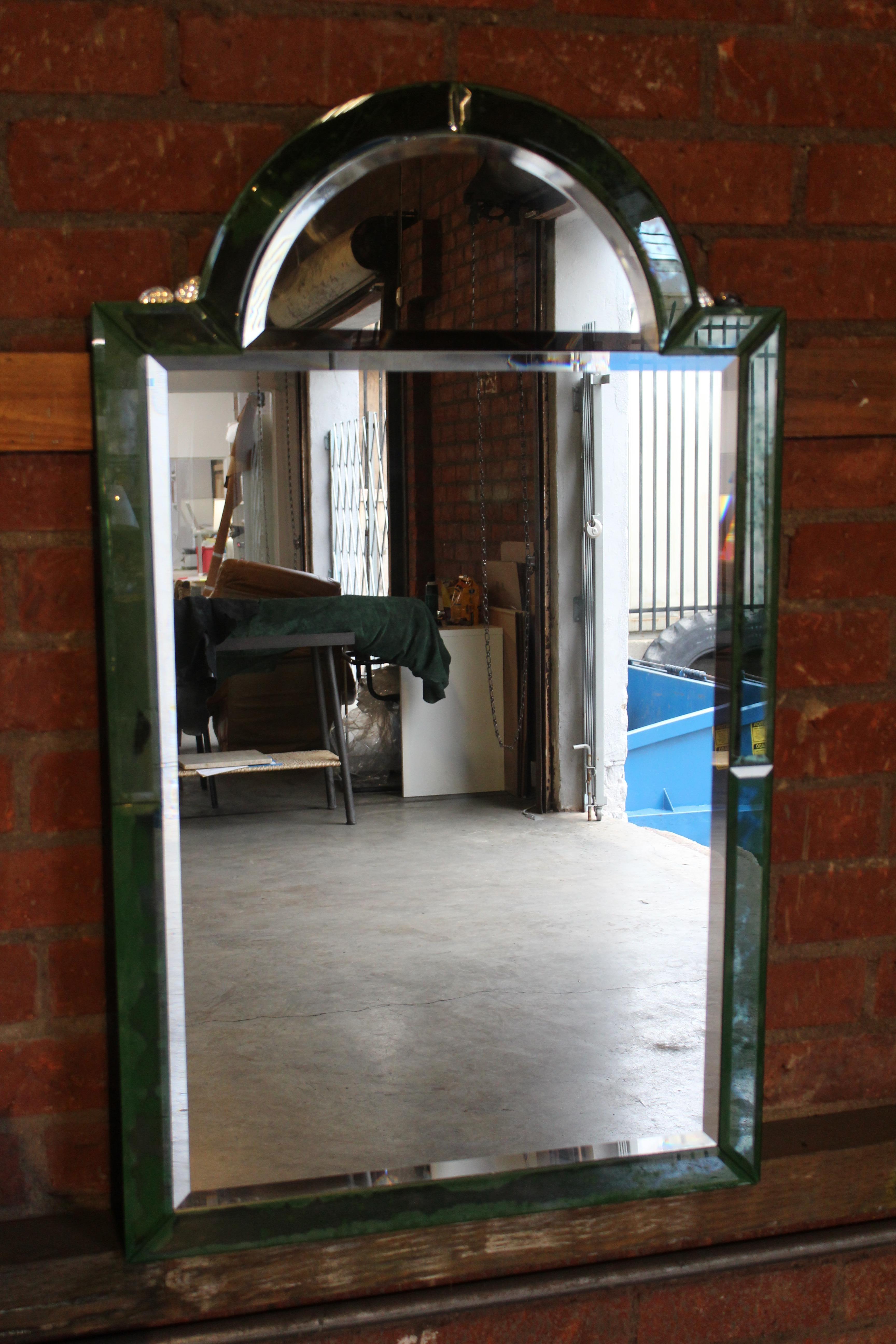 A vintage beveled glass mirror with green accents.
