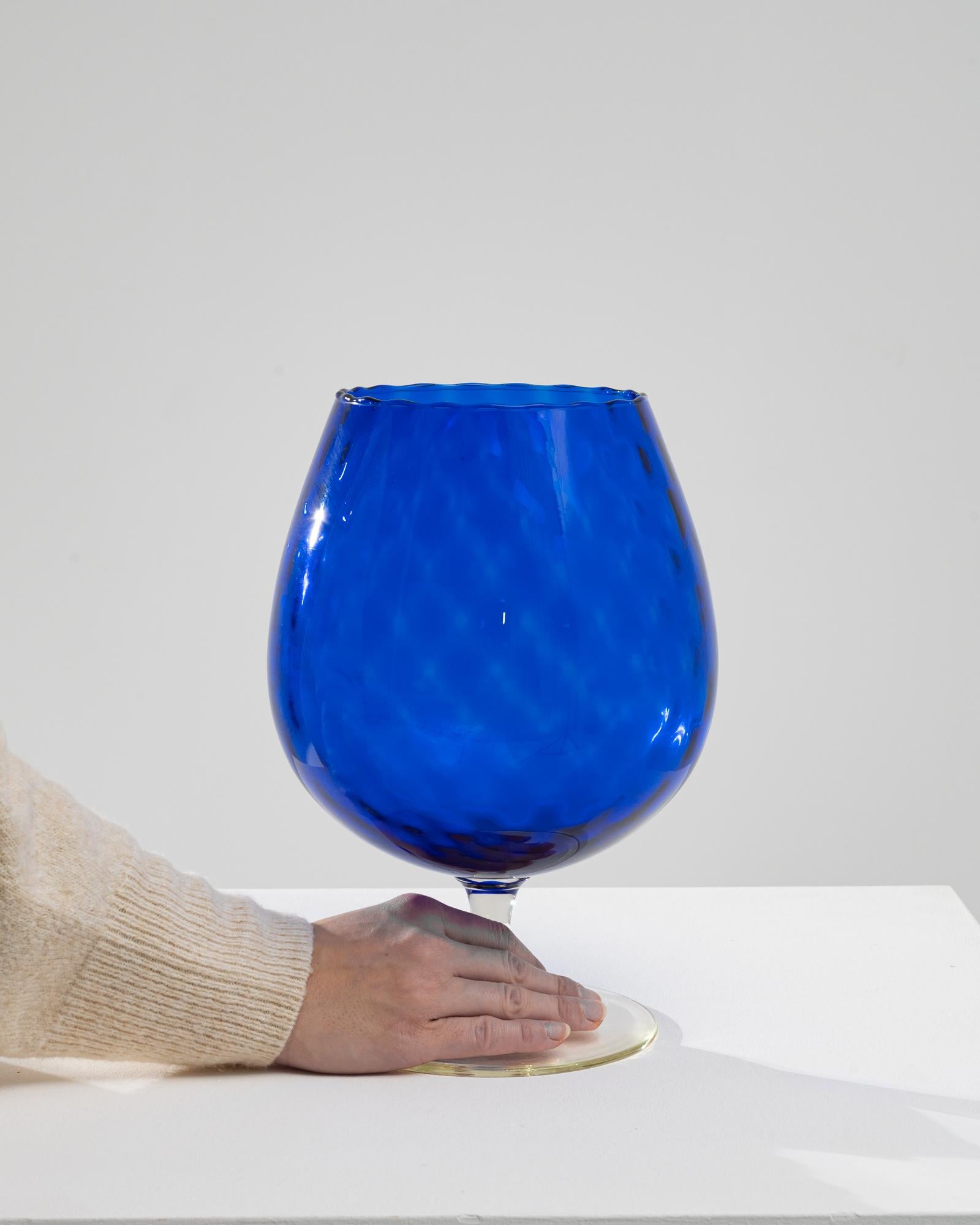 Elevate your dining experience with this exquisite 1960s Italian Blue Glass Goblet, a true testament to timeless elegance and artisanal craftsmanship. This stunning piece, originating from the vibrant heart of Italy's glassblowing tradition,