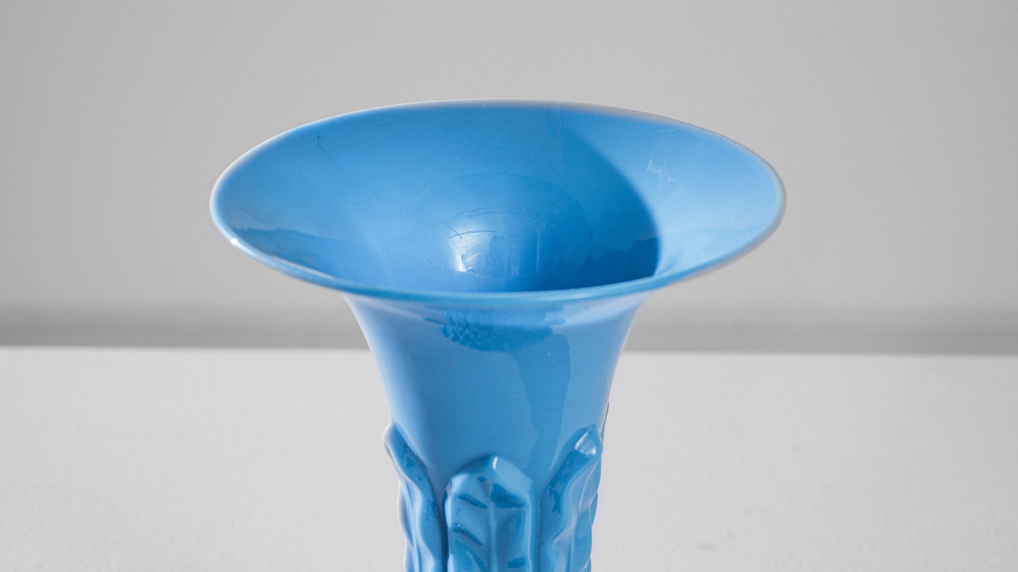 This captivating 1960s Italian blue glass vase is a stunning representation of artistry and craftsmanship from the era. With its vivid sky-blue color and unique texture, the vase has a striking presence that commands attention. The lower half boasts