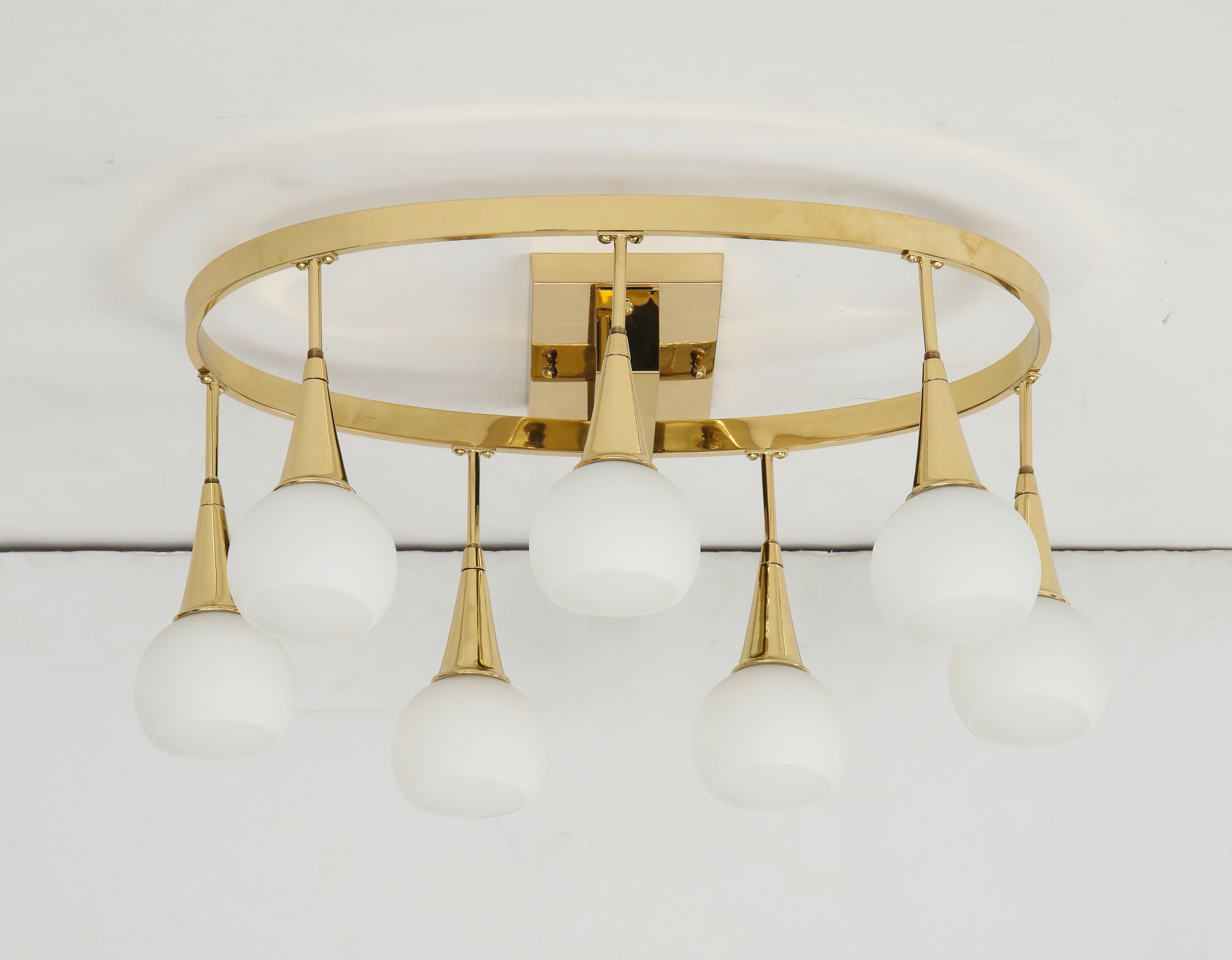 1960s Italian flush mount chandelier.
The polished Oval Brass frame supports seven white glass globes
each with their own light source that have been newly rewired for the US.