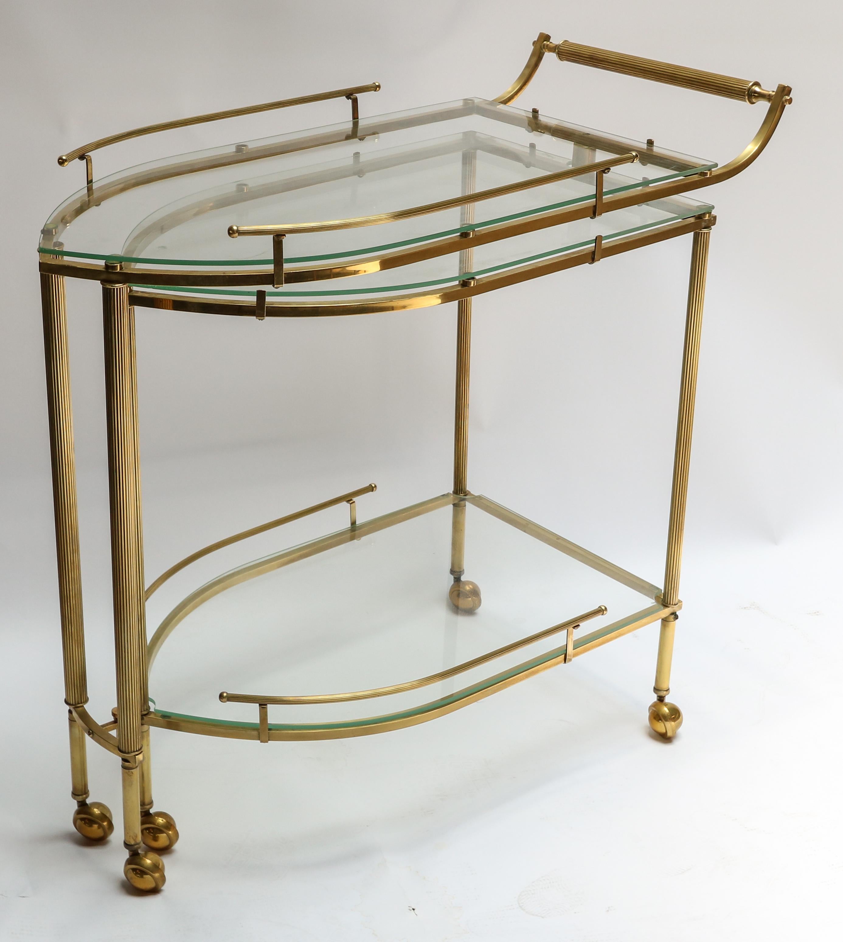 Italian brass bar cart from the 1960s with three glass shelves, fluted legs and ball wheels. The bottom section swings out to provide access to the lower upper shelf.